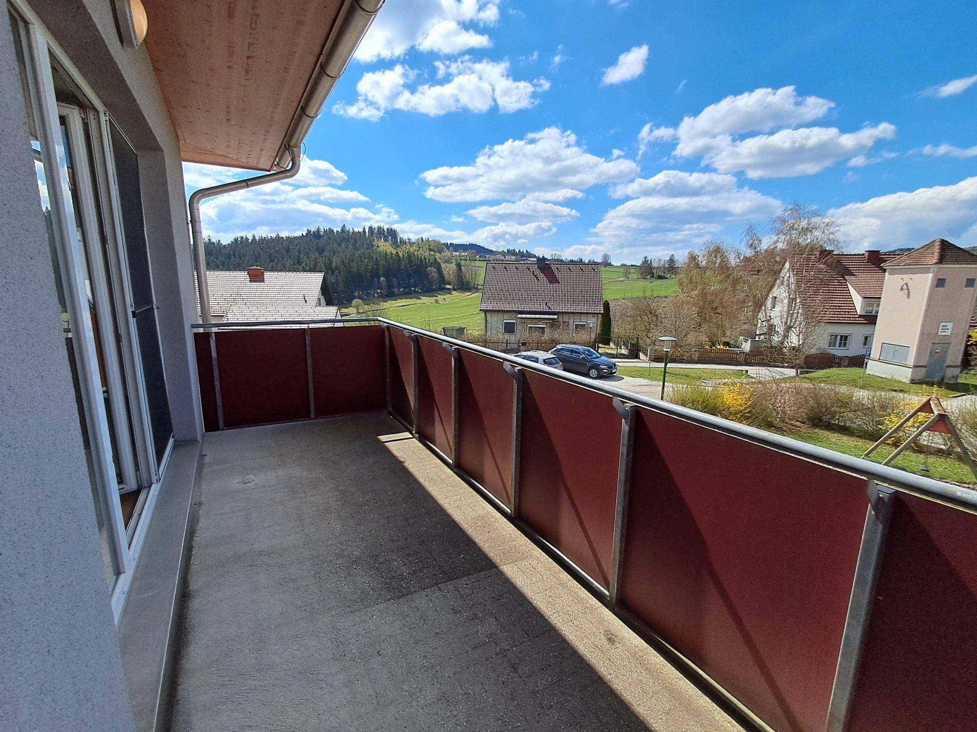 Geräumiger Balkon mit weitem Blick über die ländliche Umgebung unter blauem Himmel.