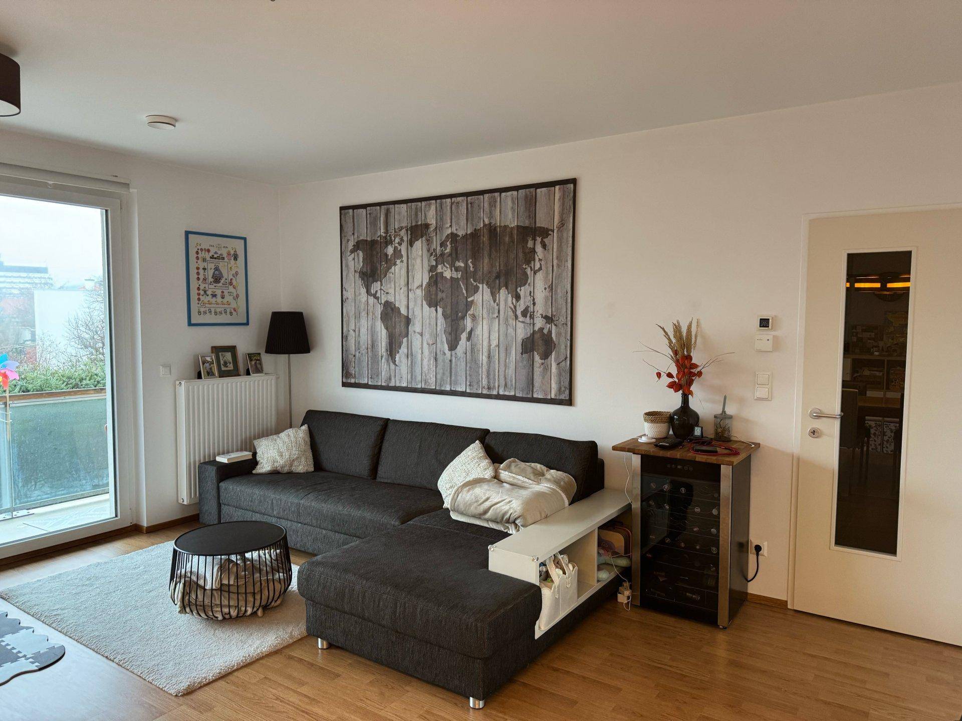 Gemütliches Wohnzimmer mit Ecksofa, Teppich und dekorativer Weltkarte an der Wand.