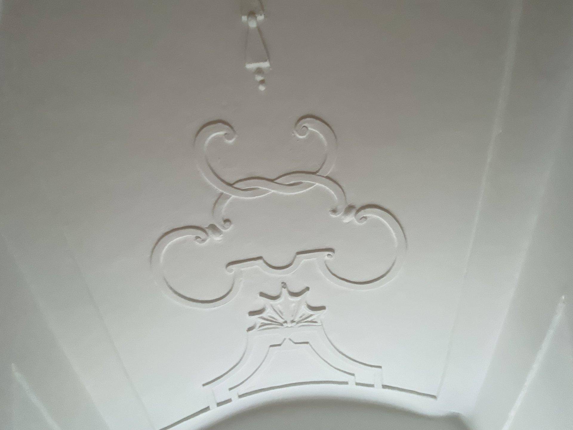 Detailaufnahme einer kunstvollen Stuckverzierung an einer gewölbten Decke.