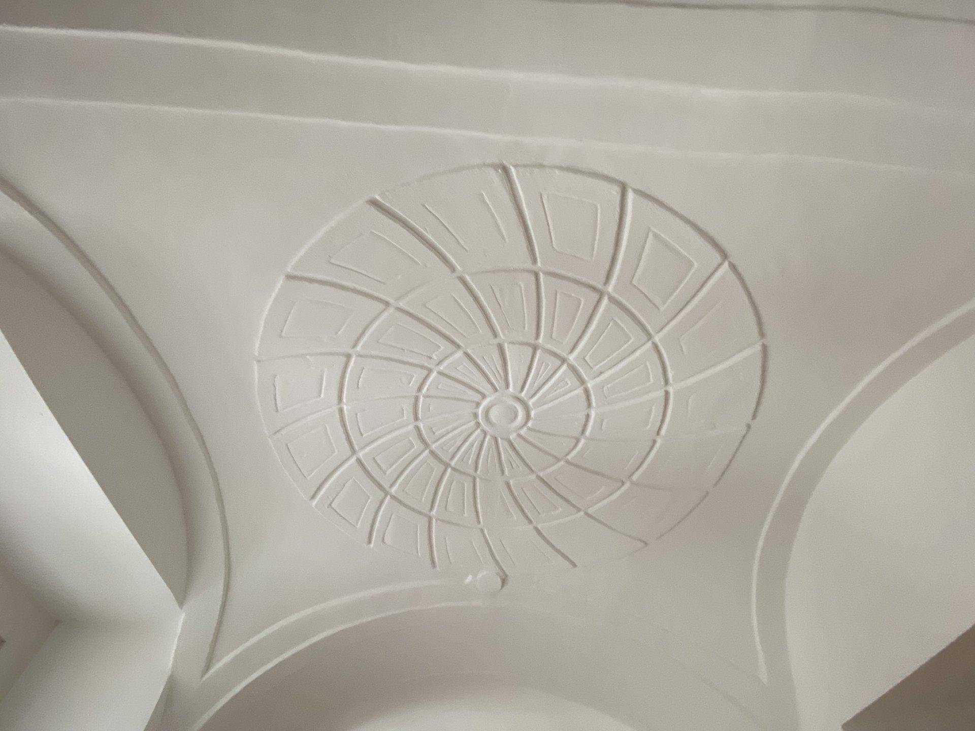 Gewölbte Decke mit einzigartiger, spiralförmiger Stuckverzierung in hellem Weißton, die ein besonderes Ambiente schafft.