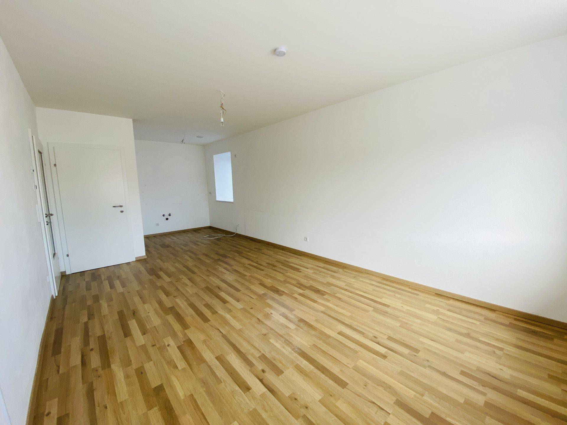 Leerer Raum mit Holzparkettboden und einem kleinen Fenster, ideal für individuelle Gestaltung.