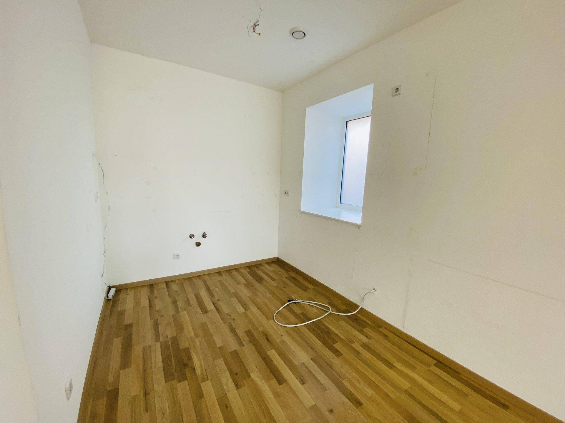 Kleiner, heller Raum mit Holzparkettboden und Anschlüssen an der Wand, vielseitig nutzbar.