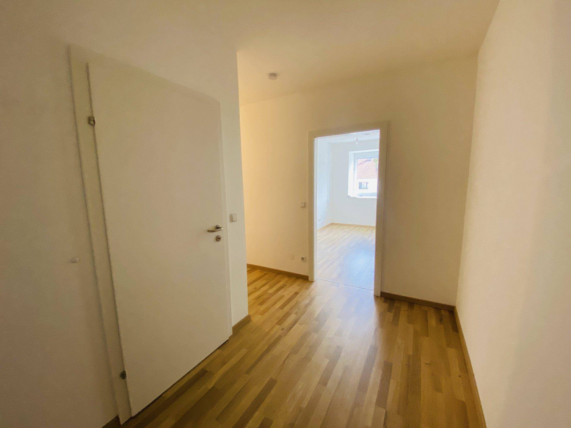 Heller Flur mit Holzparkettboden und weißen Türen, der zu weiteren Räumen führt.