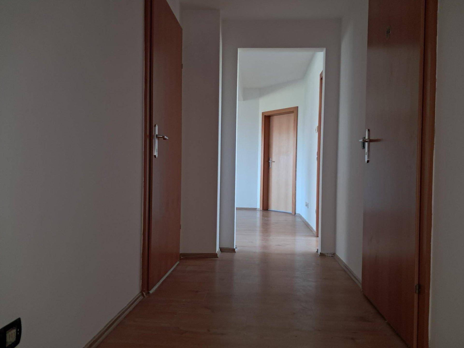 Heller Flur mit hellem Holzboden und weißen Wänden, der zu weiteren Räumen führt.