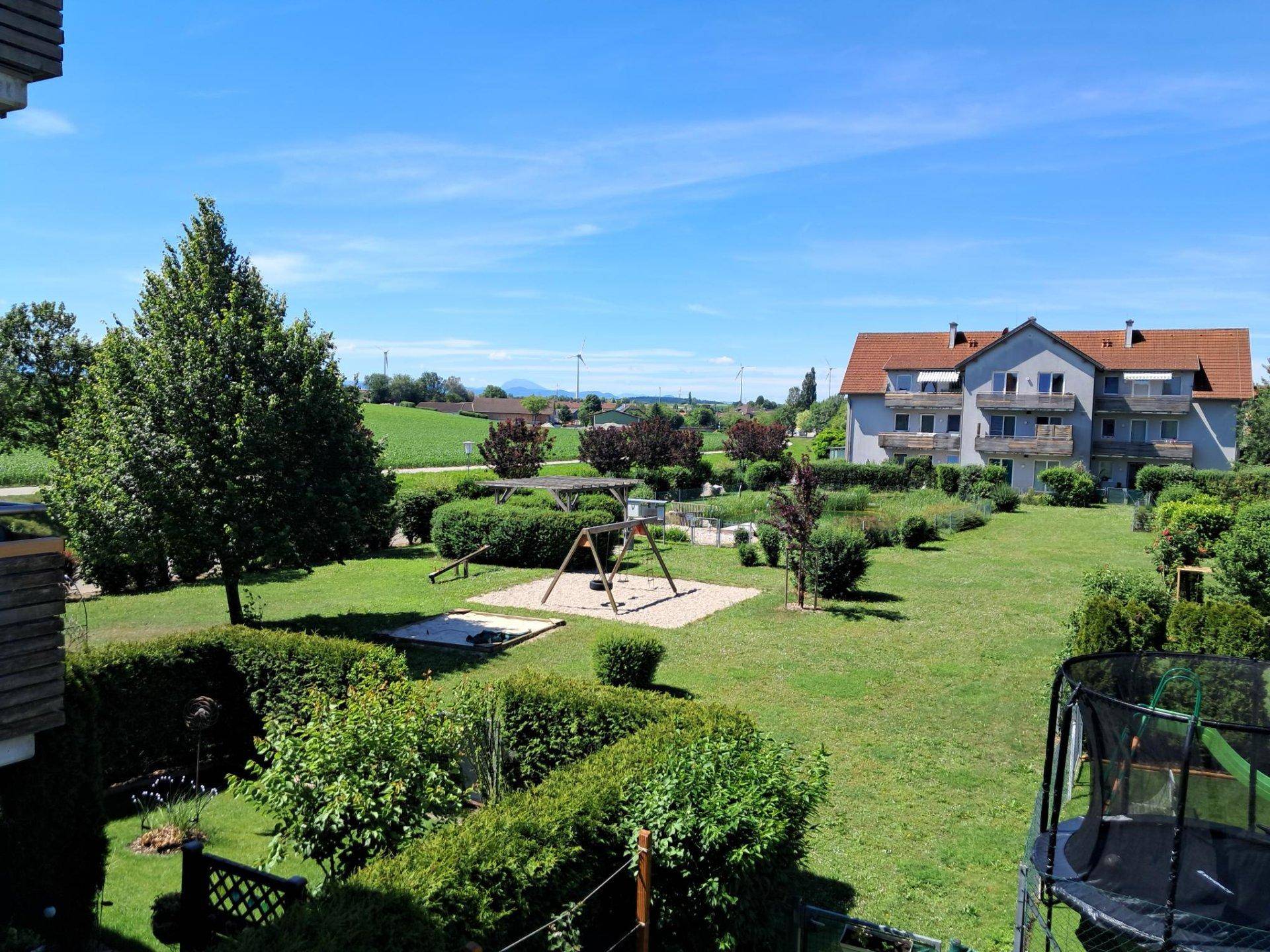 Panoramablick vom Balkon auf die gepflegte Grünanlage mit Spielplatz und weitem Landblick.
