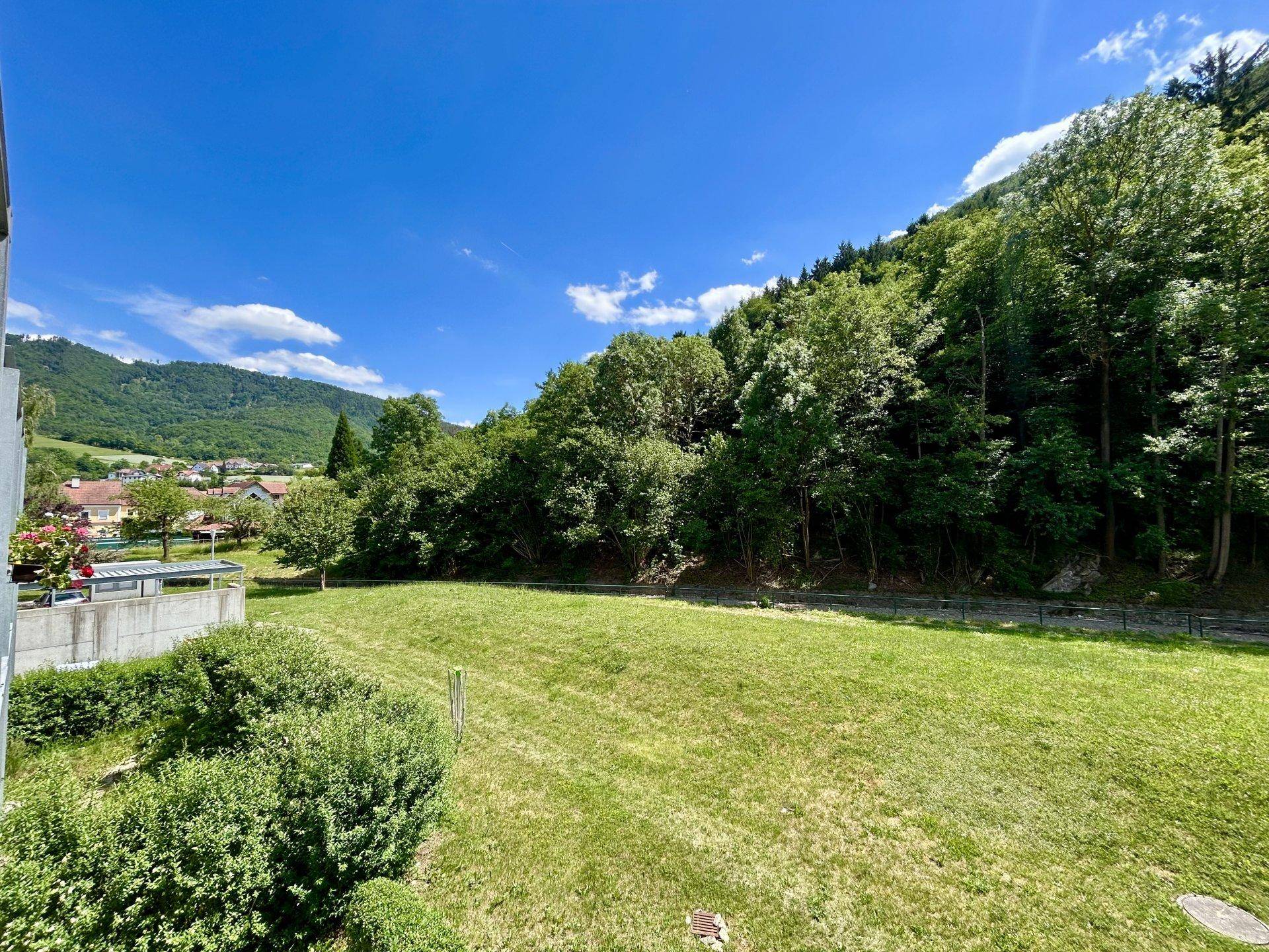 Weitläufiger Blick von einem Balkon auf grüne Hügel und eine ländliche Umgebung.