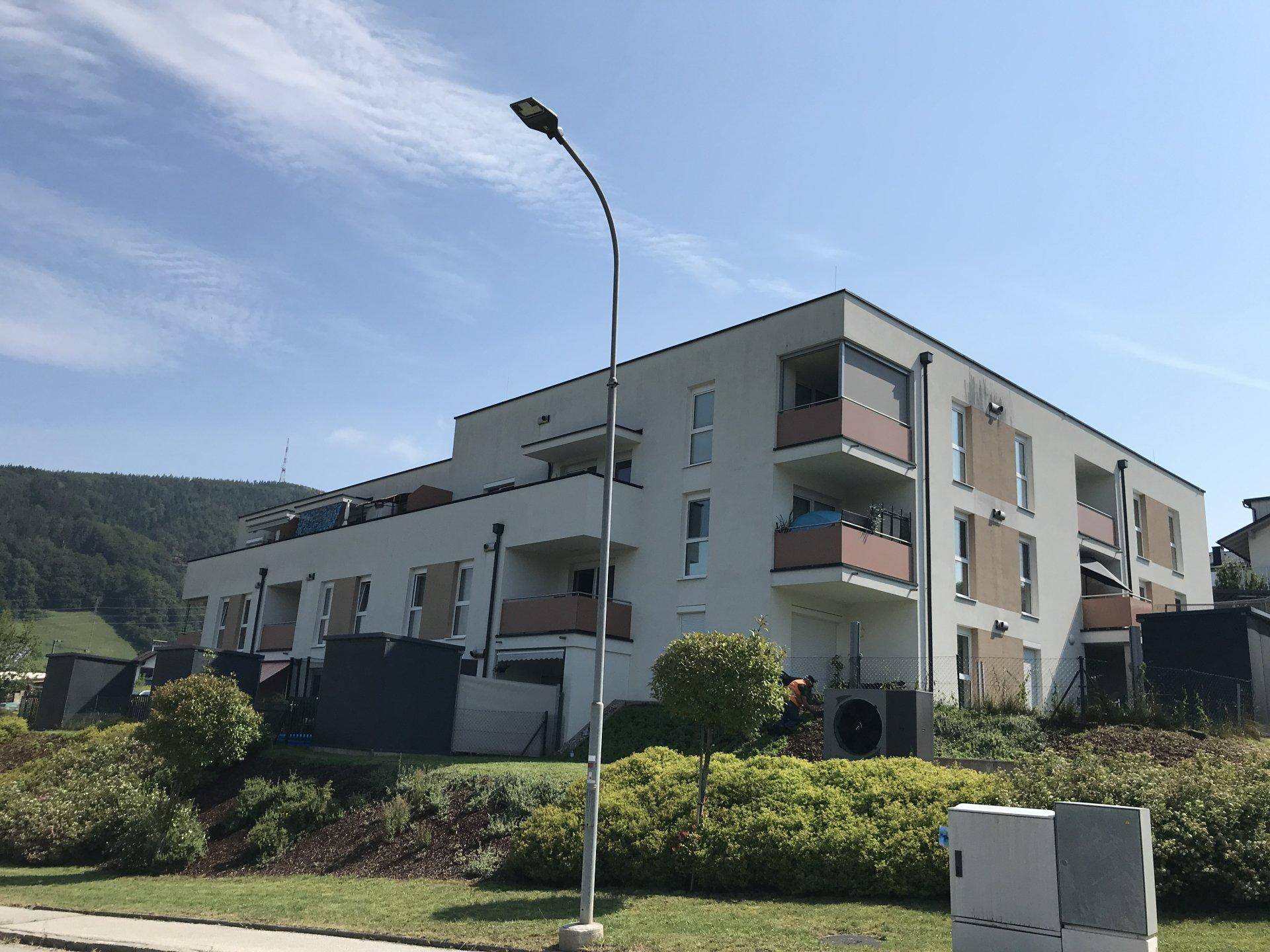 Moderne Wohnanlage mit Balkonen und Blick auf die umliegende grüne Hügellandschaft.