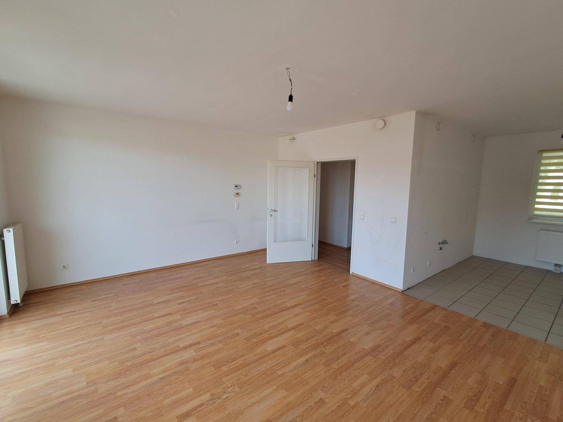 Geräumiger Wohnbereich mit Laminat- und Fliesenboden, bereit für individuelle Gestaltung.