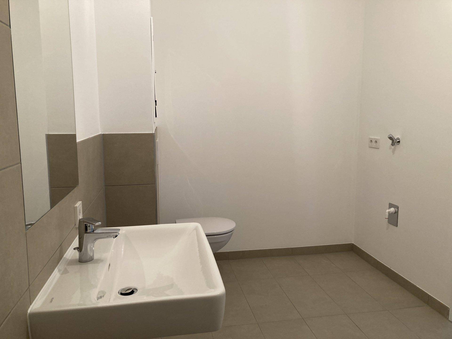 Helles Gäste-WC mit modernem Waschbecken, Wand-WC und neutralen Fliesen am Boden und an der Wand.
