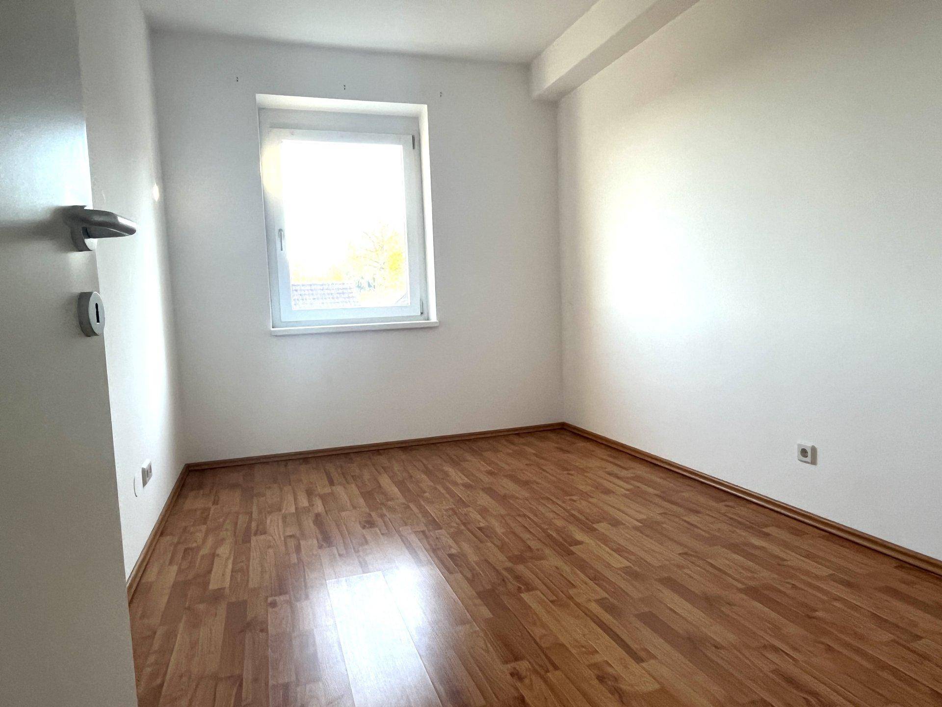 Kleineres Zimmer mit Laminatboden und einem Fenster, ideal als Kinderzimmer oder Arbeitszimmer nutzbar.
