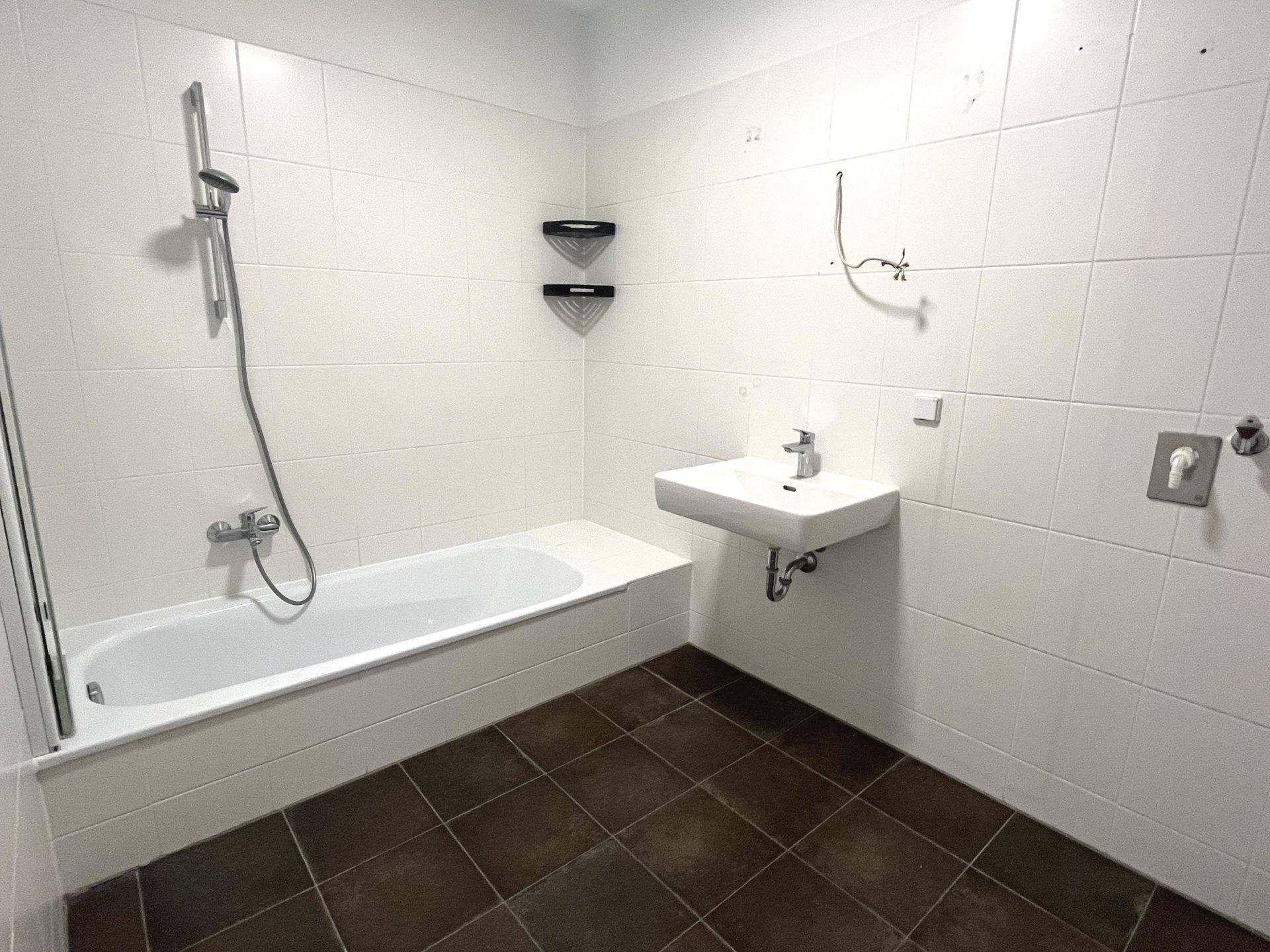 Modernes Badezimmer mit weißen Fliesen, Badewanne und Waschbecken, bereit für die Endmontage der Armaturen.