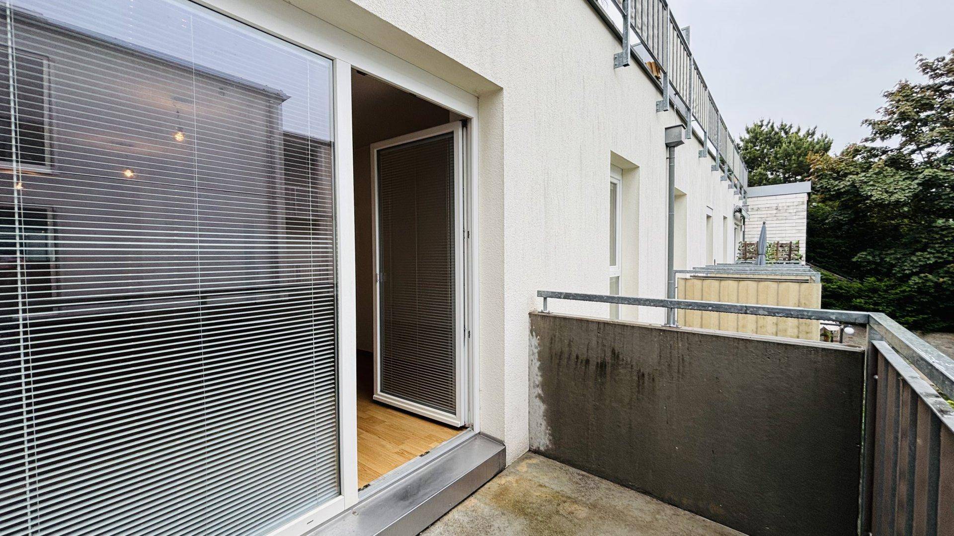 Balkon mit Zugang vom Innenraum, umgeben von einer schützenden Brüstung und Blick ins Grüne.