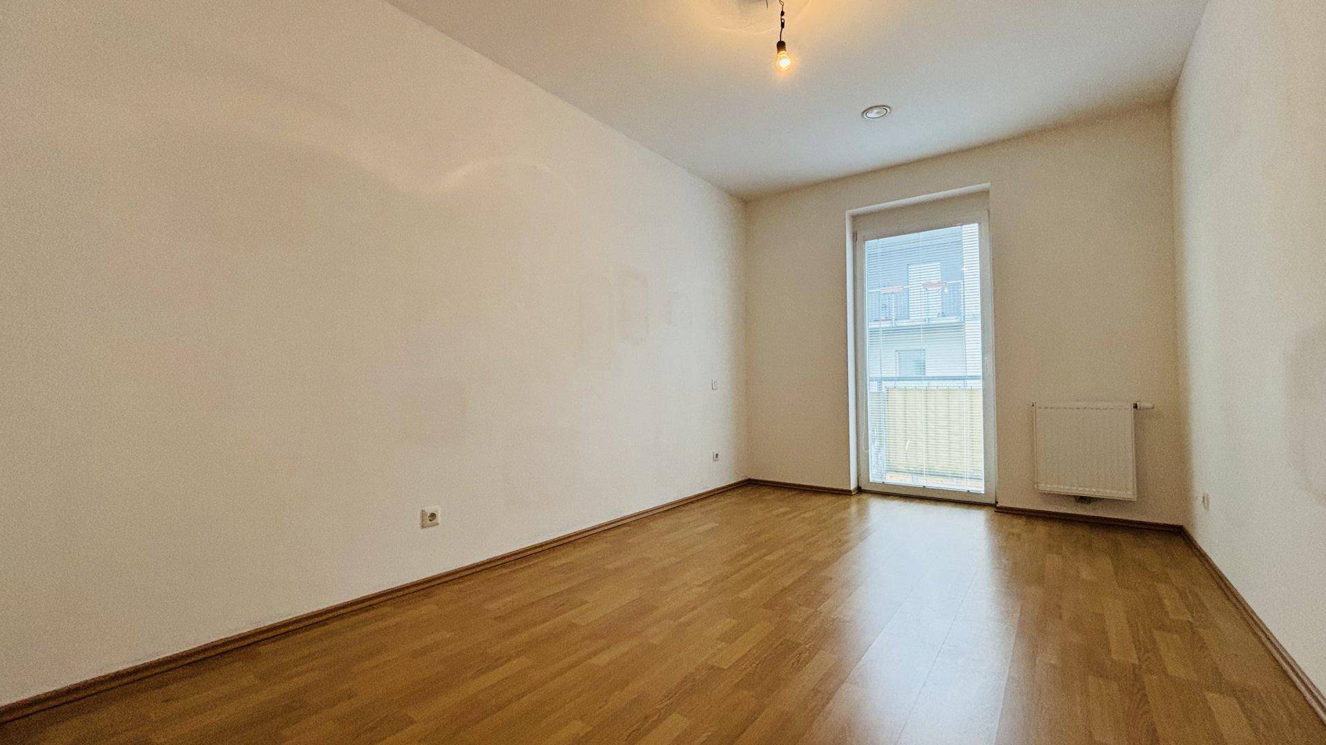 Geräumiges Schlafzimmer mit Parkettboden und Zugang zu einem französischen Balkon, hell und einladend.