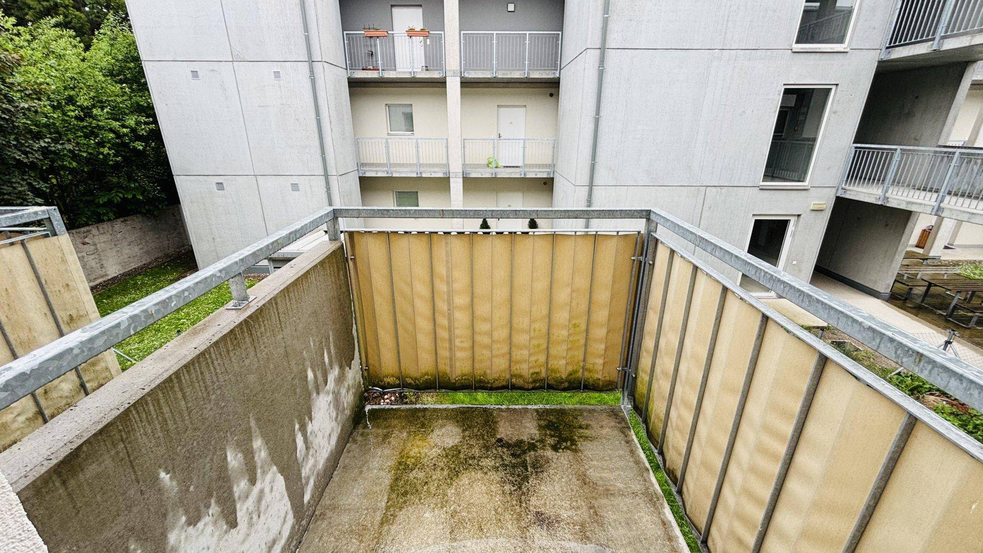 Balkon mit Sichtschutz und Blick auf die umliegenden Gebäude und Grünflächen.