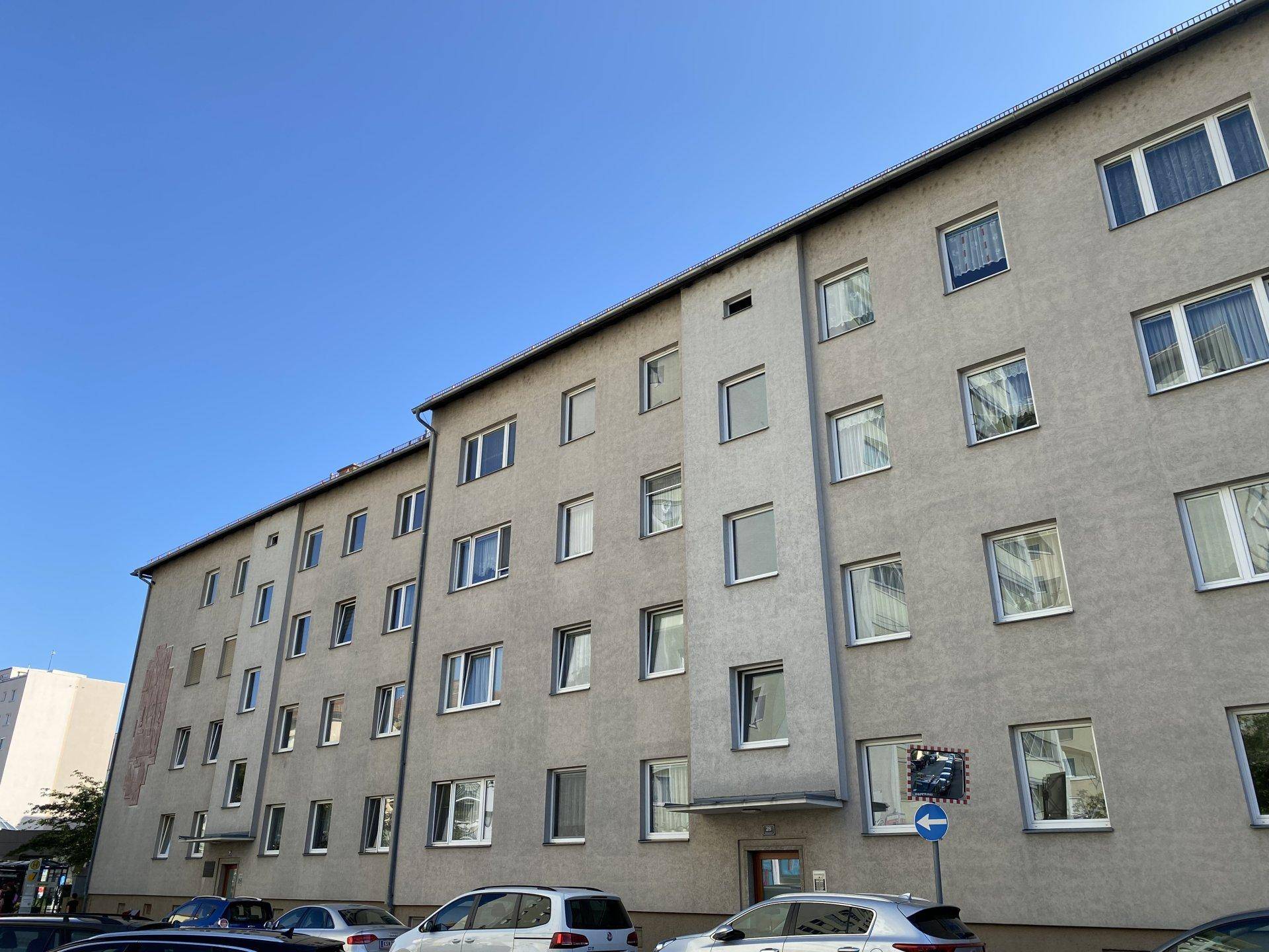Detailansicht der Fassade eines Wohngebäudes mit vielen Fenstern unter klarem blauem Himmel.
