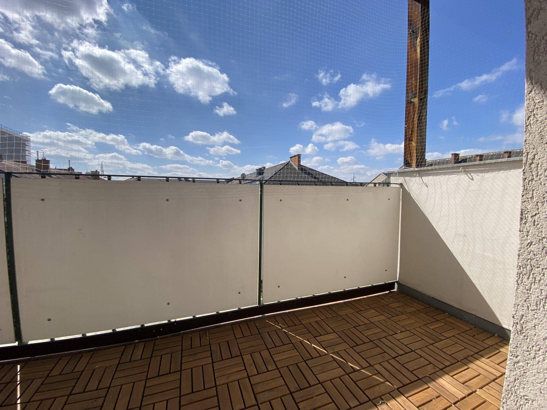 Balkon mit Holzdielenboden und Sichtschutz, ideal für entspannte Stunden im Freien.