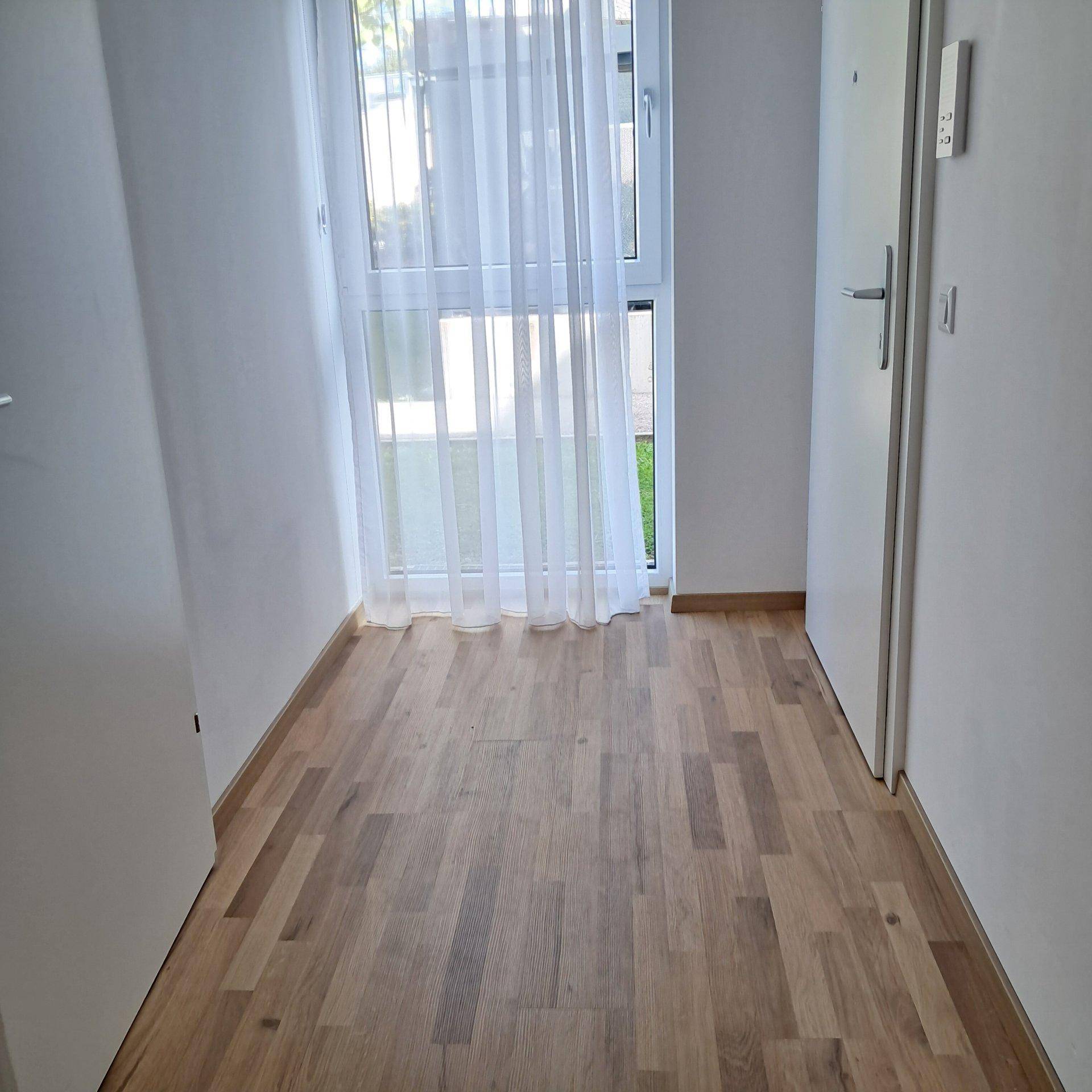 Heller Eingangsbereich mit Holzboden und großer Fenstertür.