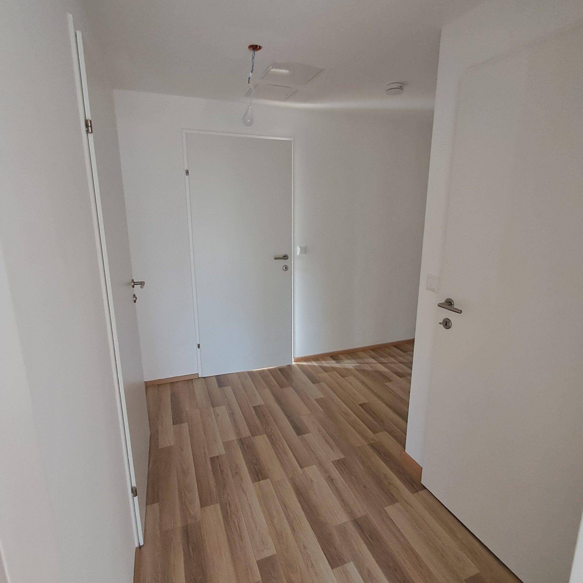 Heller Flur mit Laminatboden und weißen Türen, bereit für die individuelle Gestaltung.