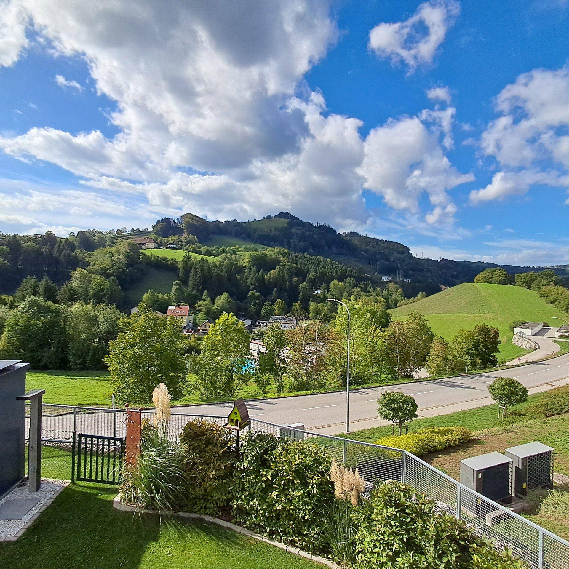 Malerischer Blick auf die grüne Hügellandschaft und die Straße unter blauem Himmel.
