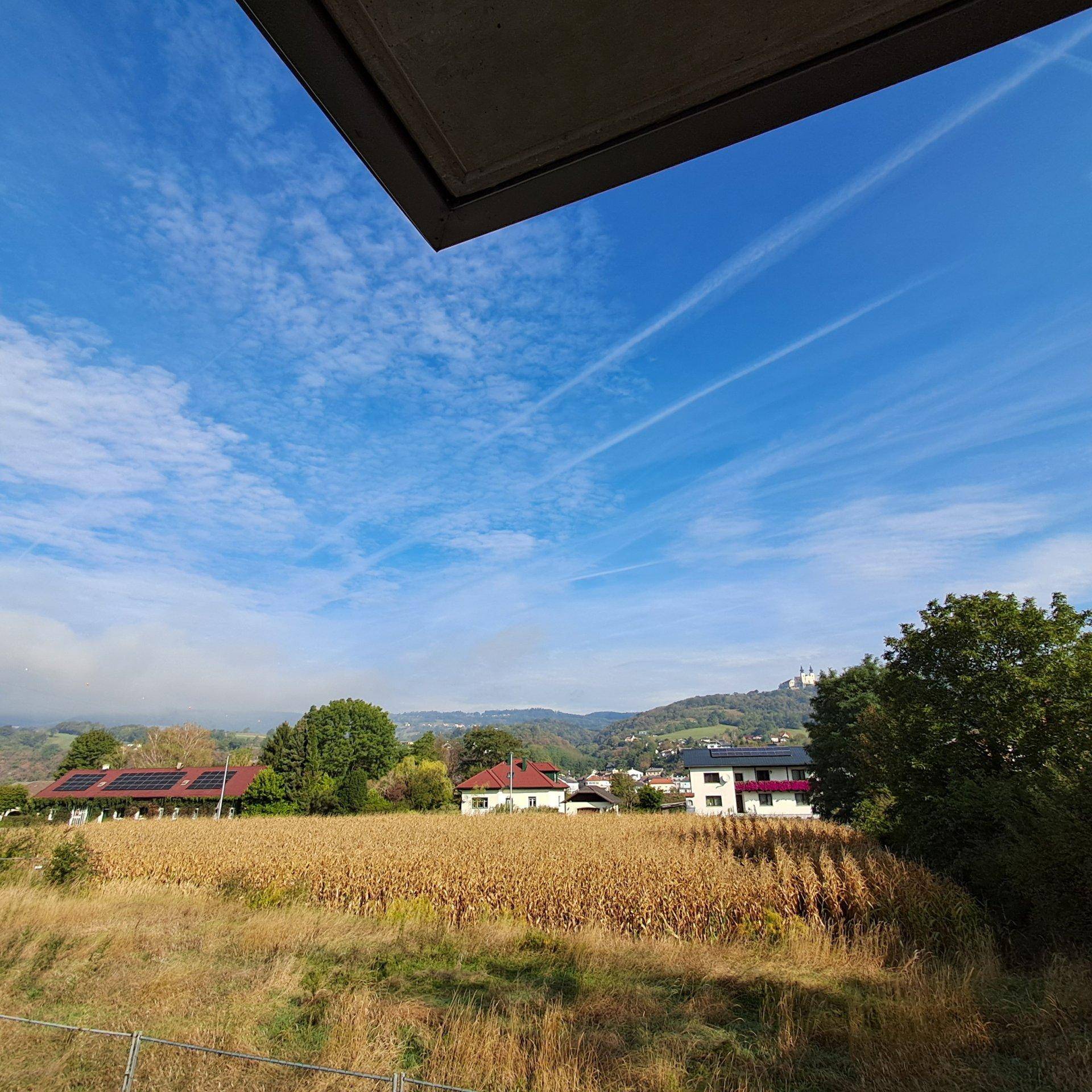 Weitläufiger Blick vom Balkon über Felder und Häuser bis zu einer Burg auf dem Hügel.