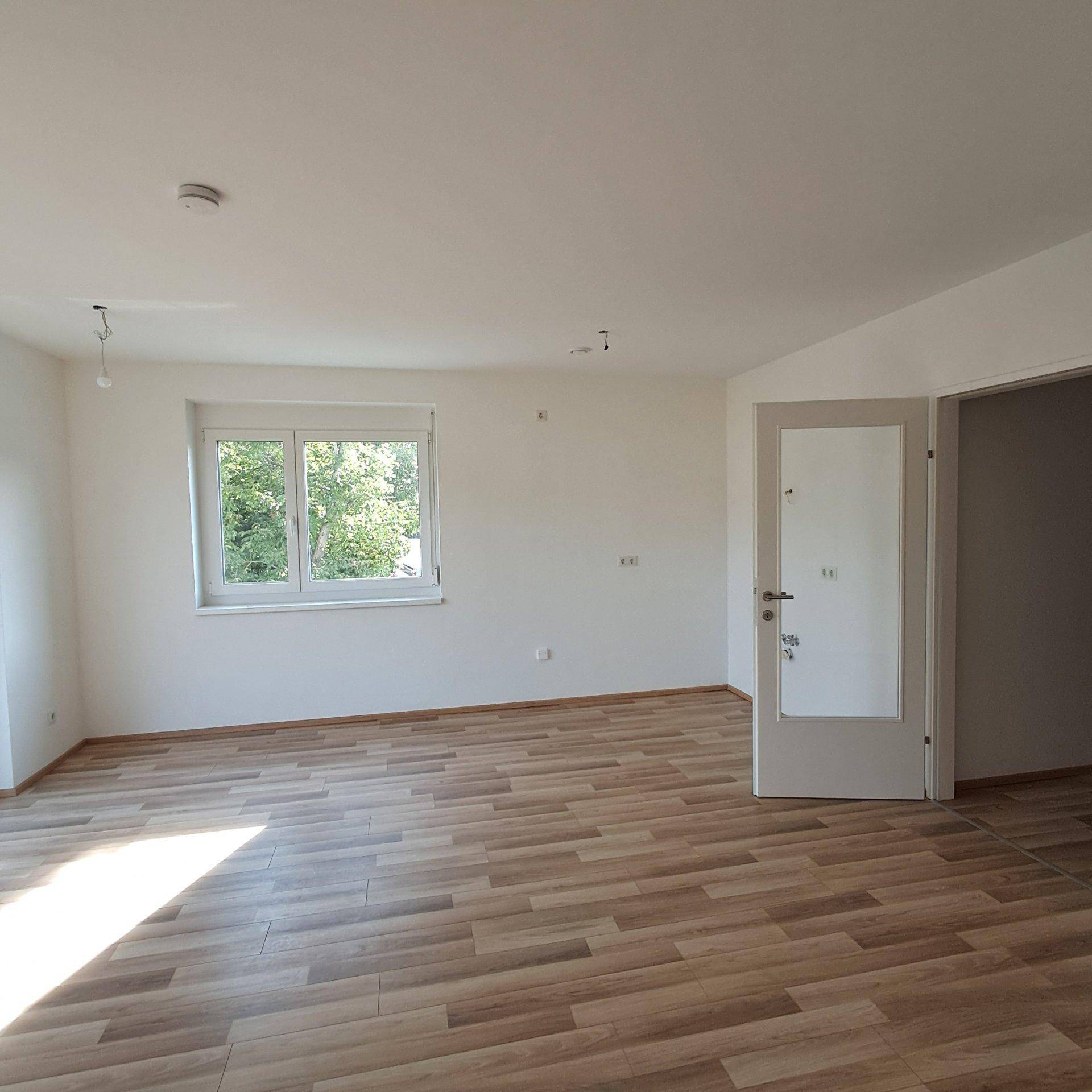 Freundlicher Raum mit Laminatboden und Fenster, das viel Tageslicht hereinlässt.