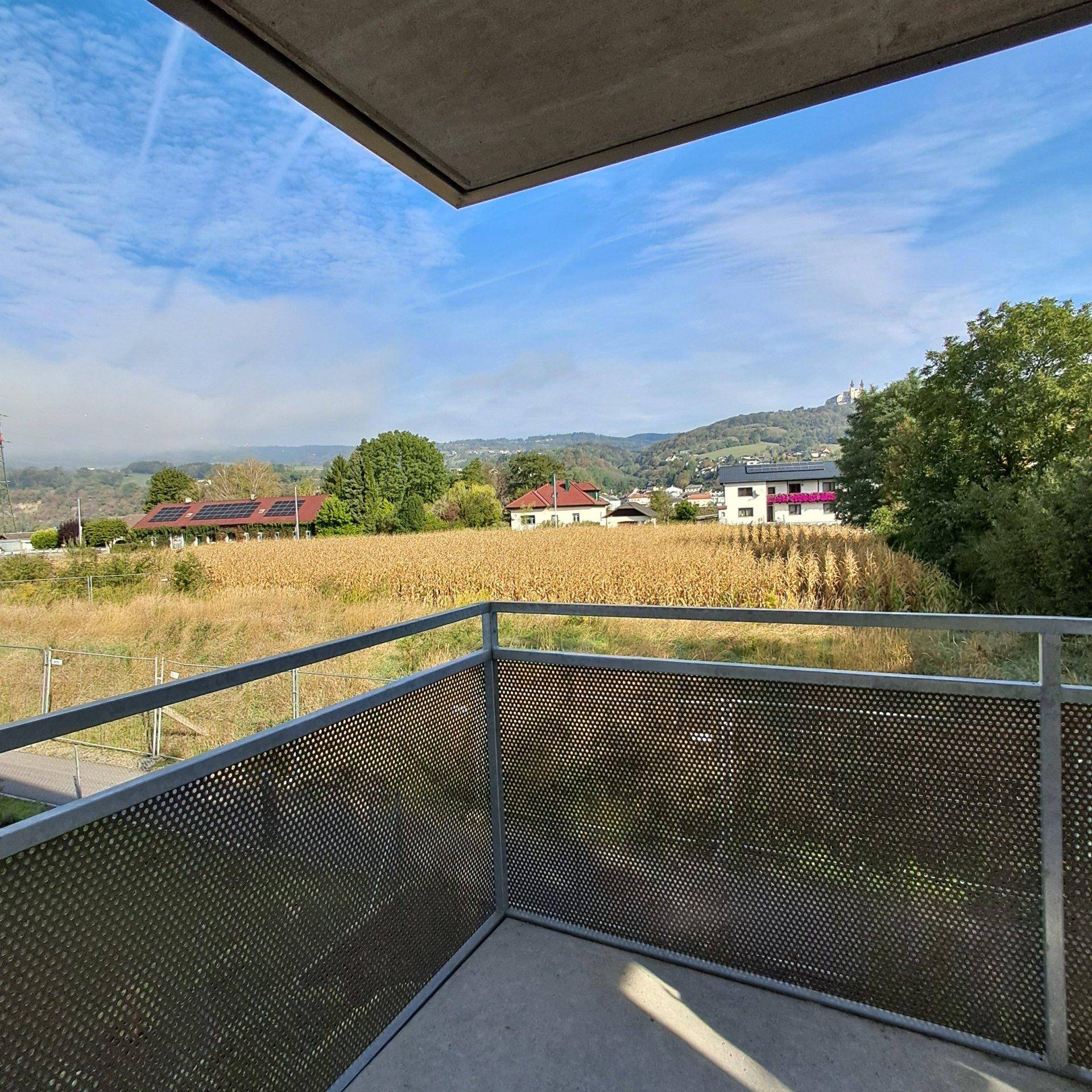 Balkon mit weitem Blick über die Landschaft, Felder und eine historische Burg.