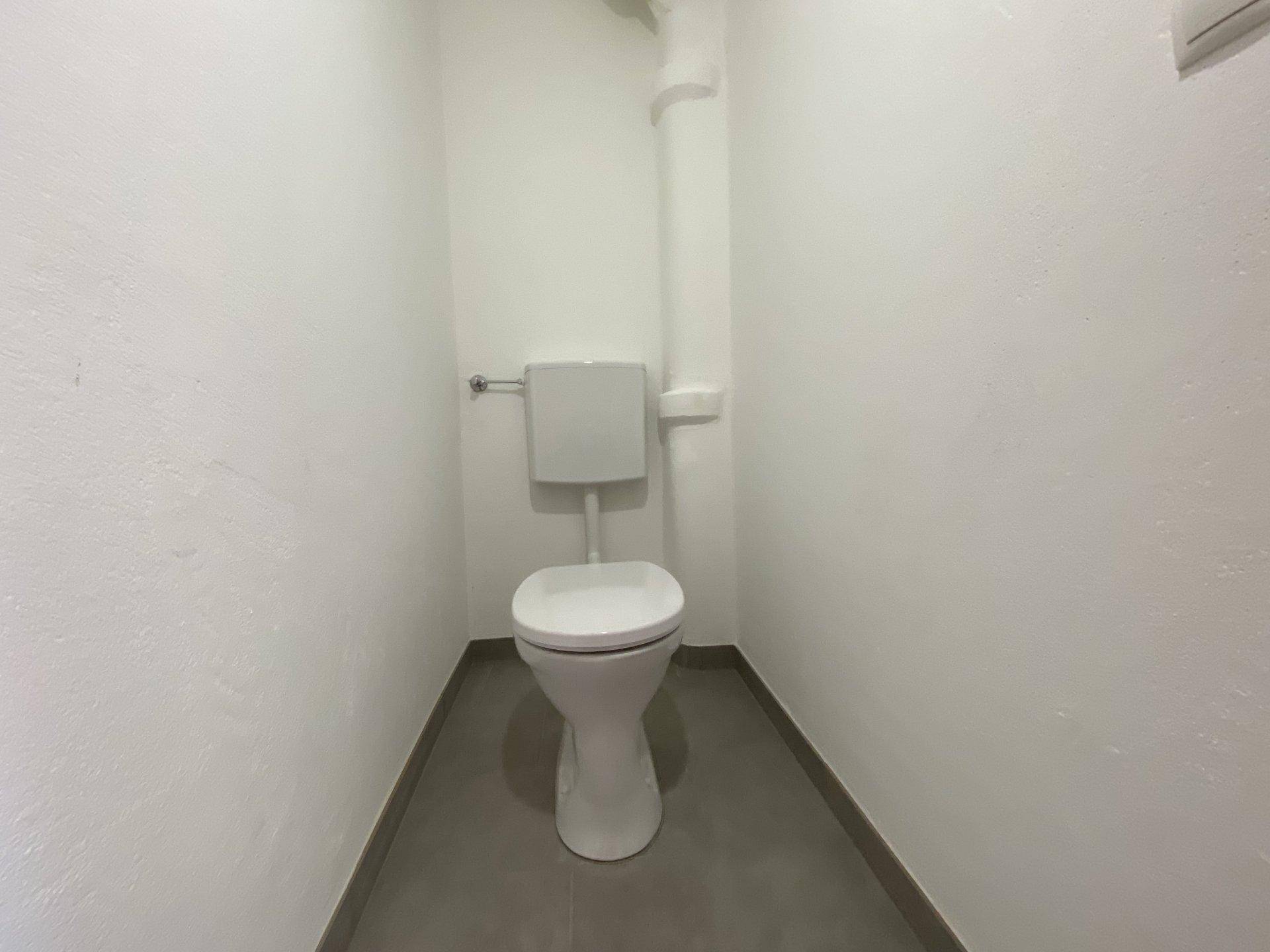 Separates WC mit Toilette und Fliesenboden, in einem sauberen und funktionalen Zustand.