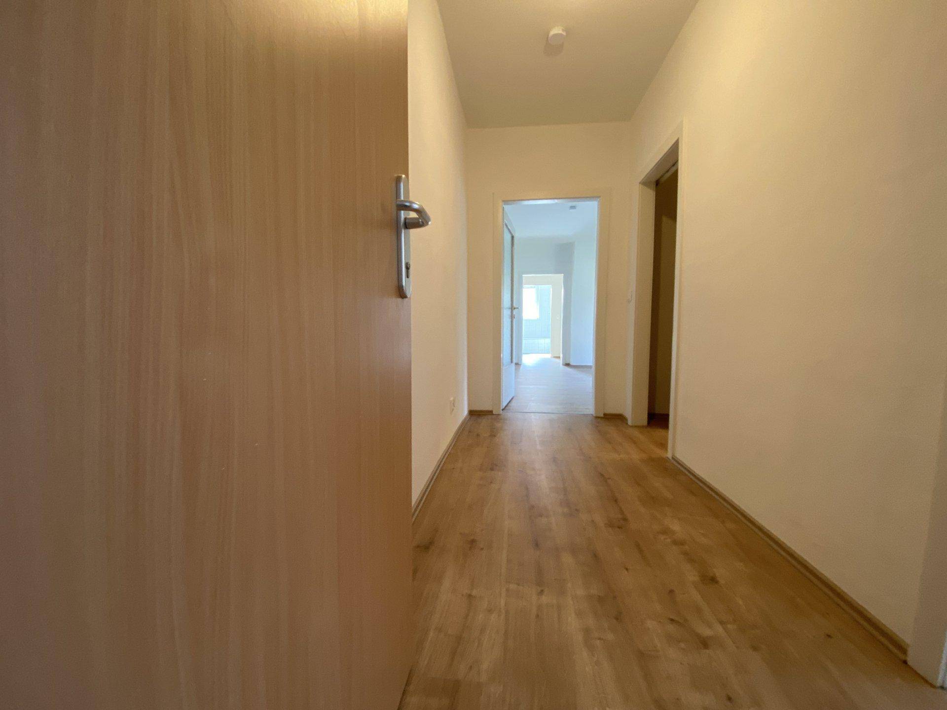 Heller Flur mit Laminatboden und Zugang zu weiteren Räumen der Wohnung.