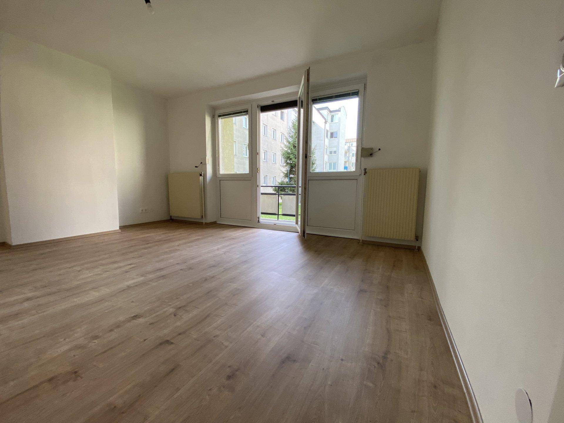 Geräumiges Zimmer mit Laminatboden und direktem Zugang zu einem Balkon.