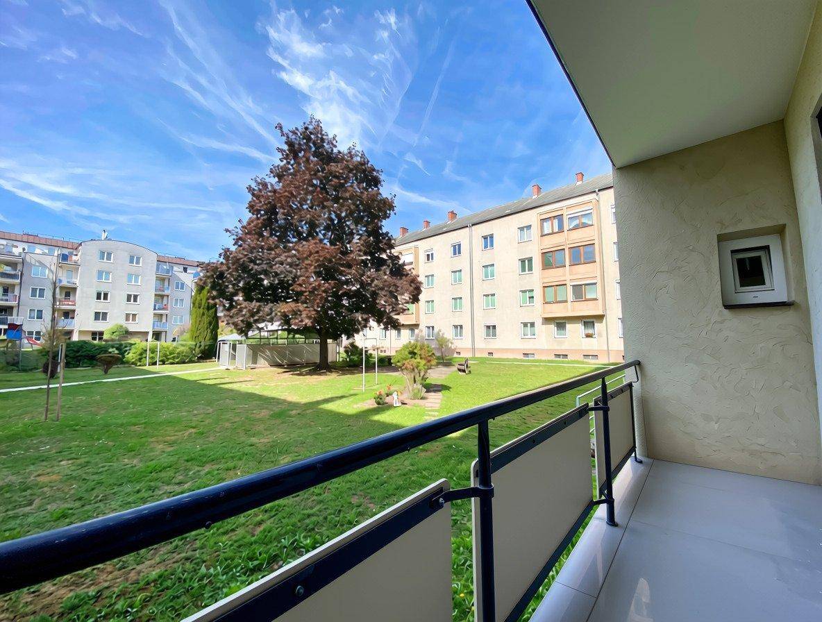 Balkon mit Blick auf den grünen Innenhof und die umliegenden Wohngebäude.