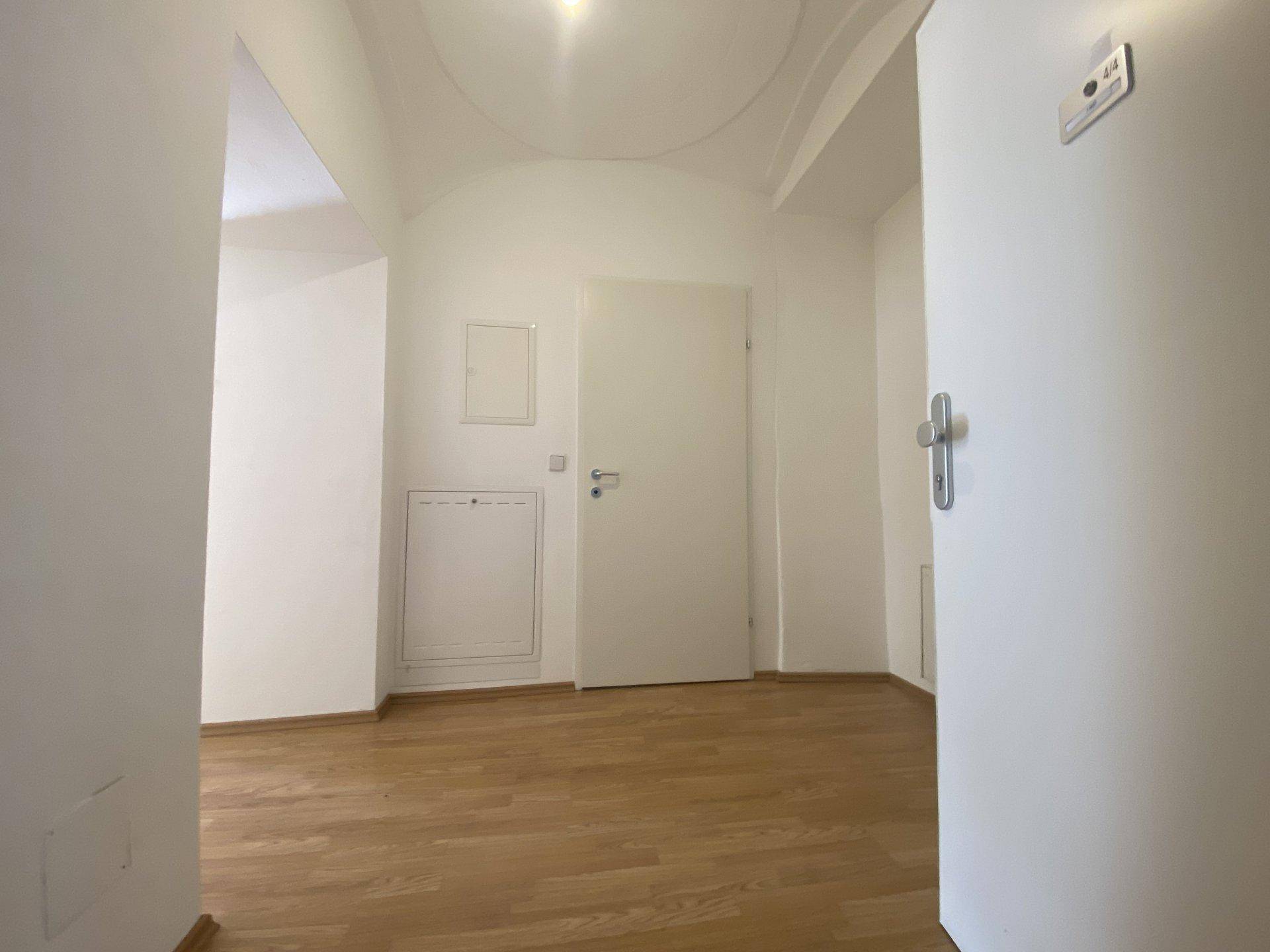 Heller Flur mit Holzboden und weißen Wänden, bereit zum Einzug.