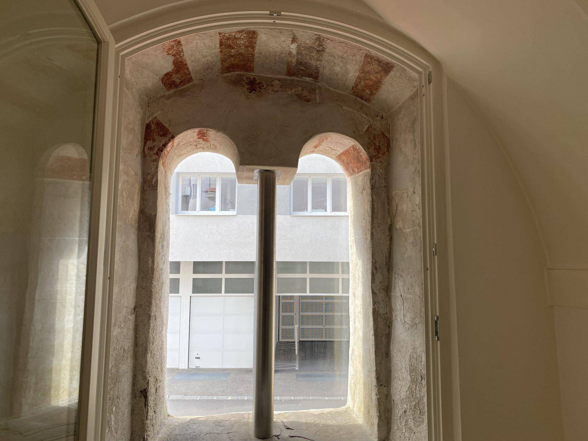 Historisches Fenster mit Steinrahmen und Blick auf den Innenhof.