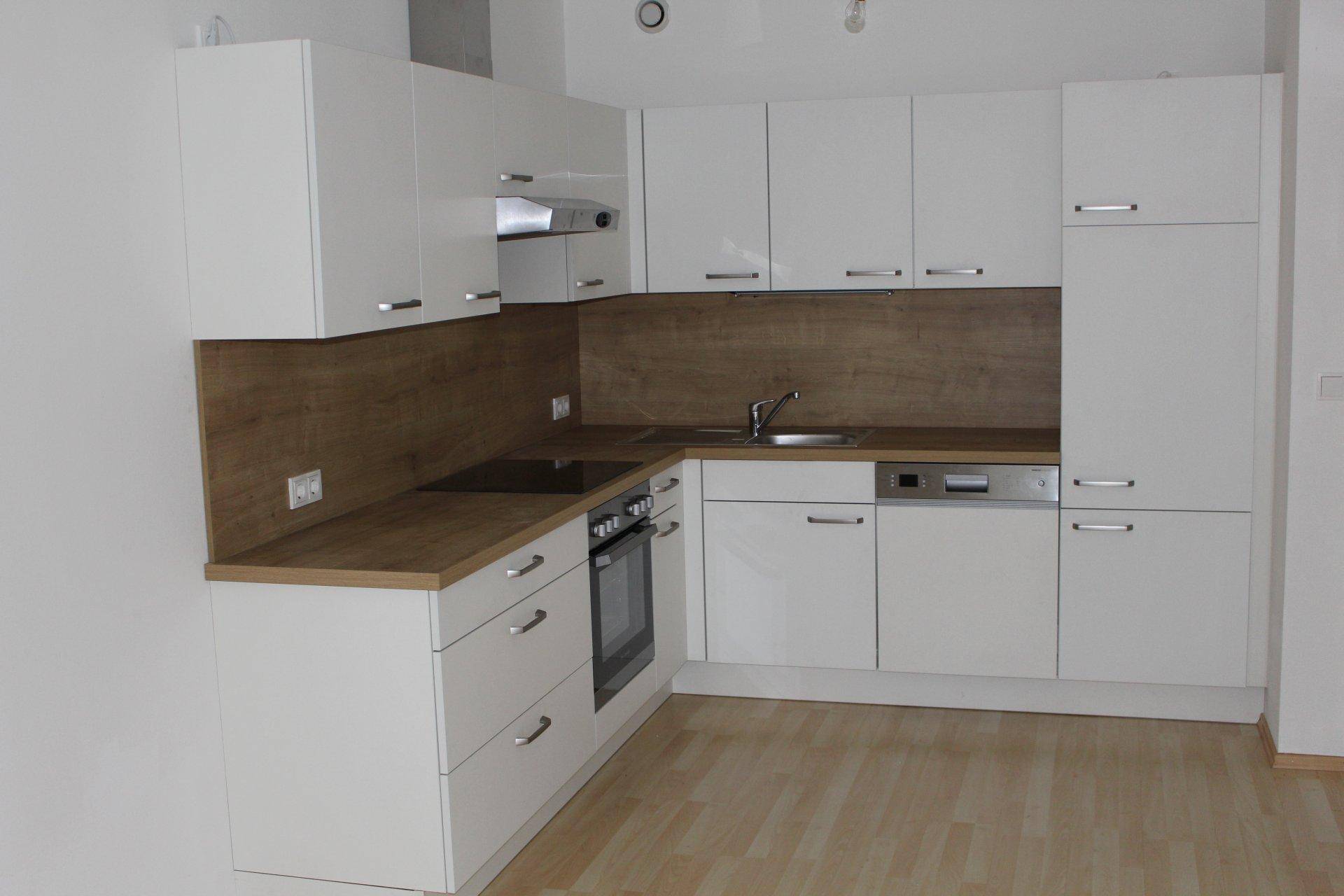 Geräumige, moderne Küche mit weißen Schränken, Holzoptik-Arbeitsplatte und integrierten Geräten.