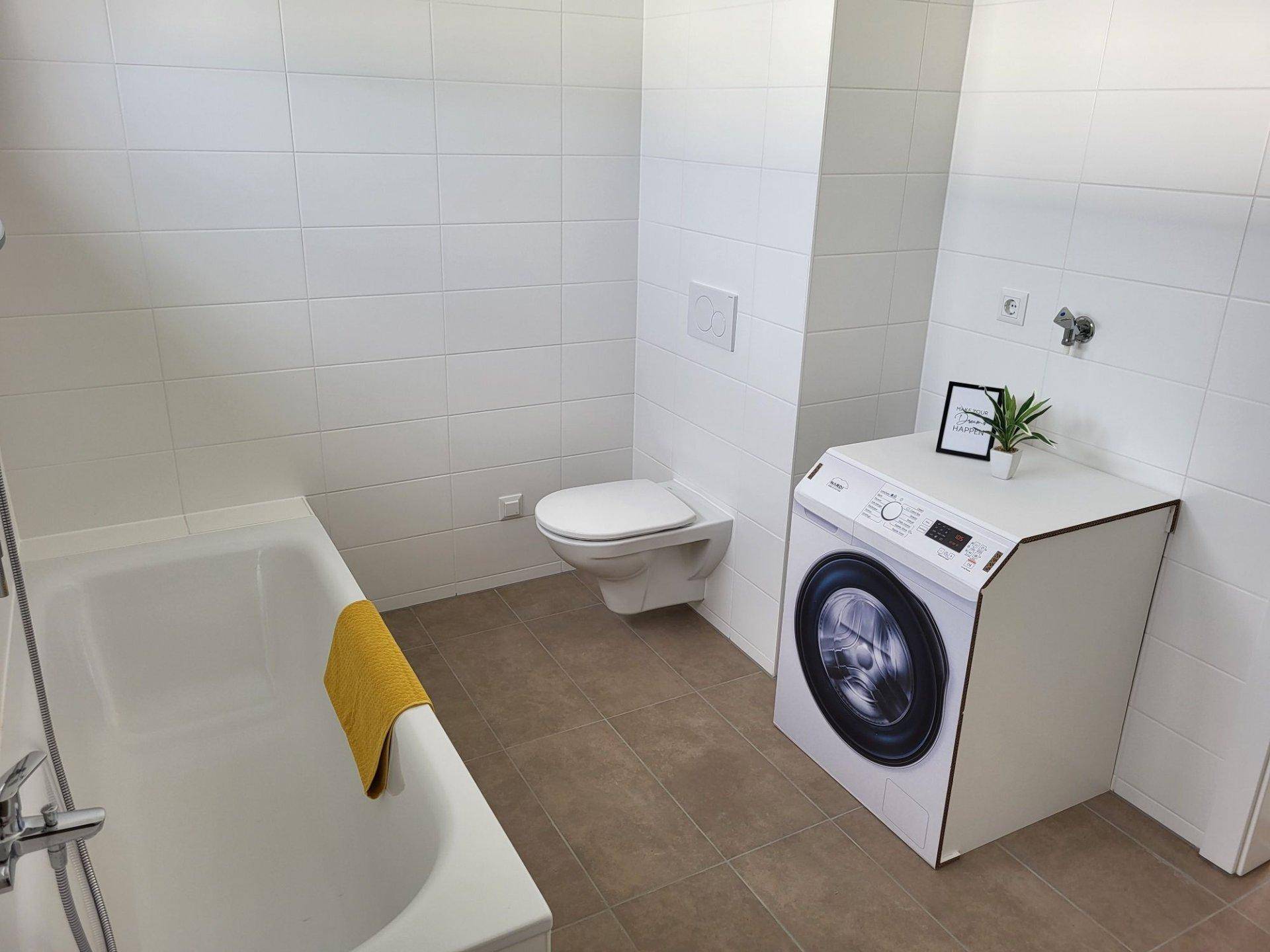 Modernes Badezimmer mit weißen Fliesen, Badewanne und wandhängendem WC.