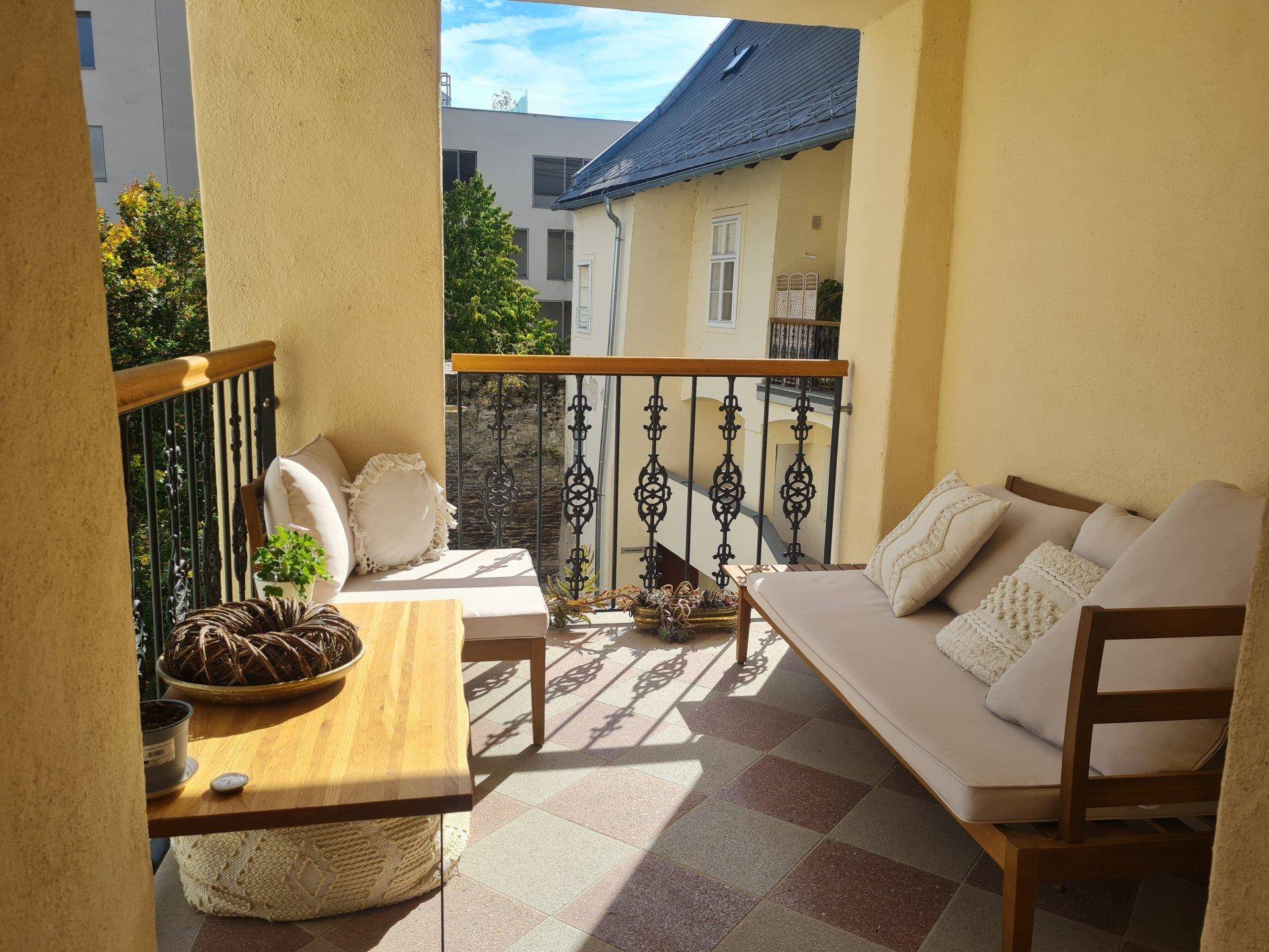 Gemütlicher Balkon mit bequemen Sitzgelegenheiten, Fliesenboden und einem angenehmen Blick ins Grüne.