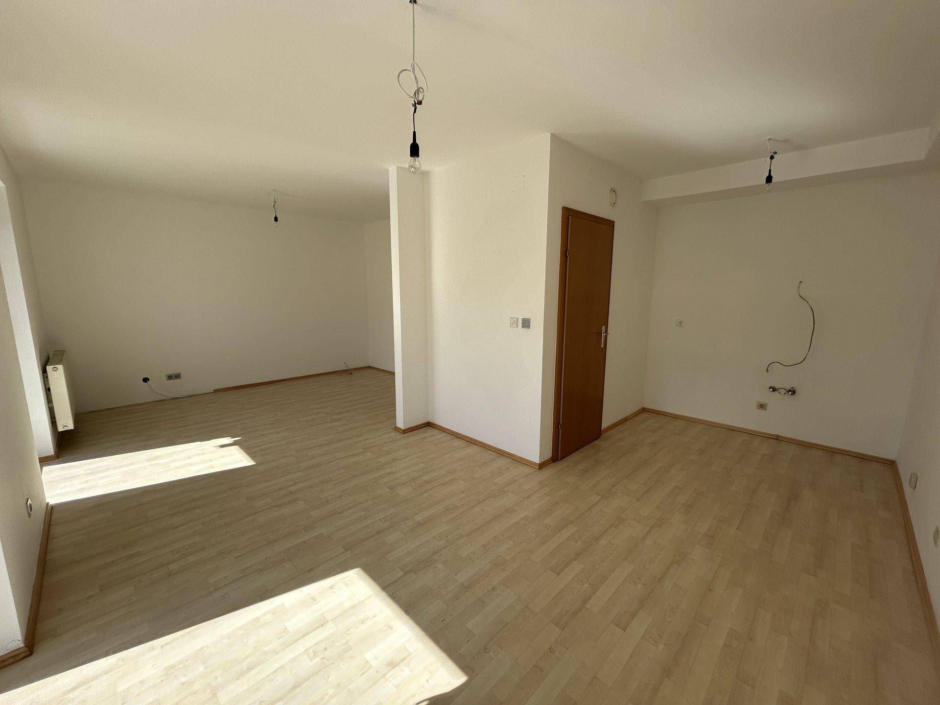 Heller Wohnbereich mit Laminatboden und neutralen Wänden, ideal für individuelle Gestaltung.