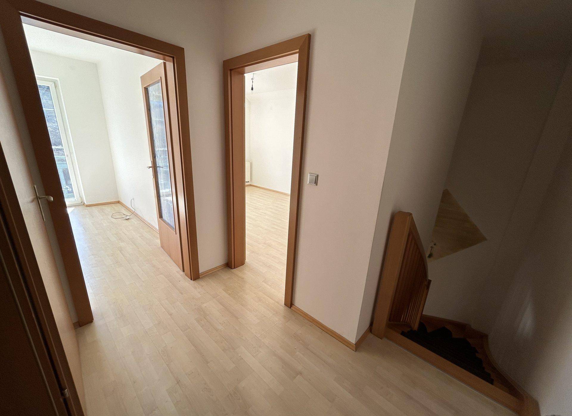 Geräumiger Flur mit mehreren Türen und Zugang zu einer Holztreppe.