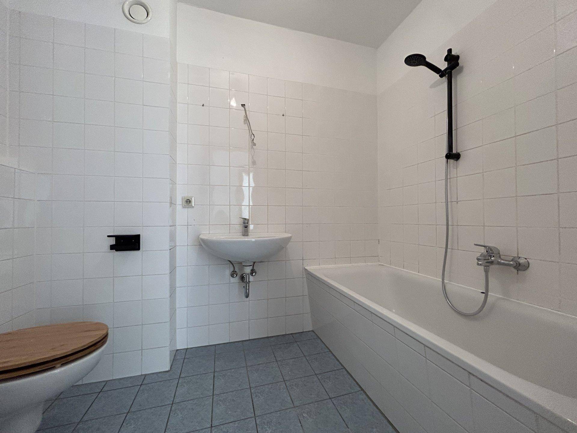 Badezimmer mit weißen Fliesen, Badewanne, Dusche und Waschbecken.