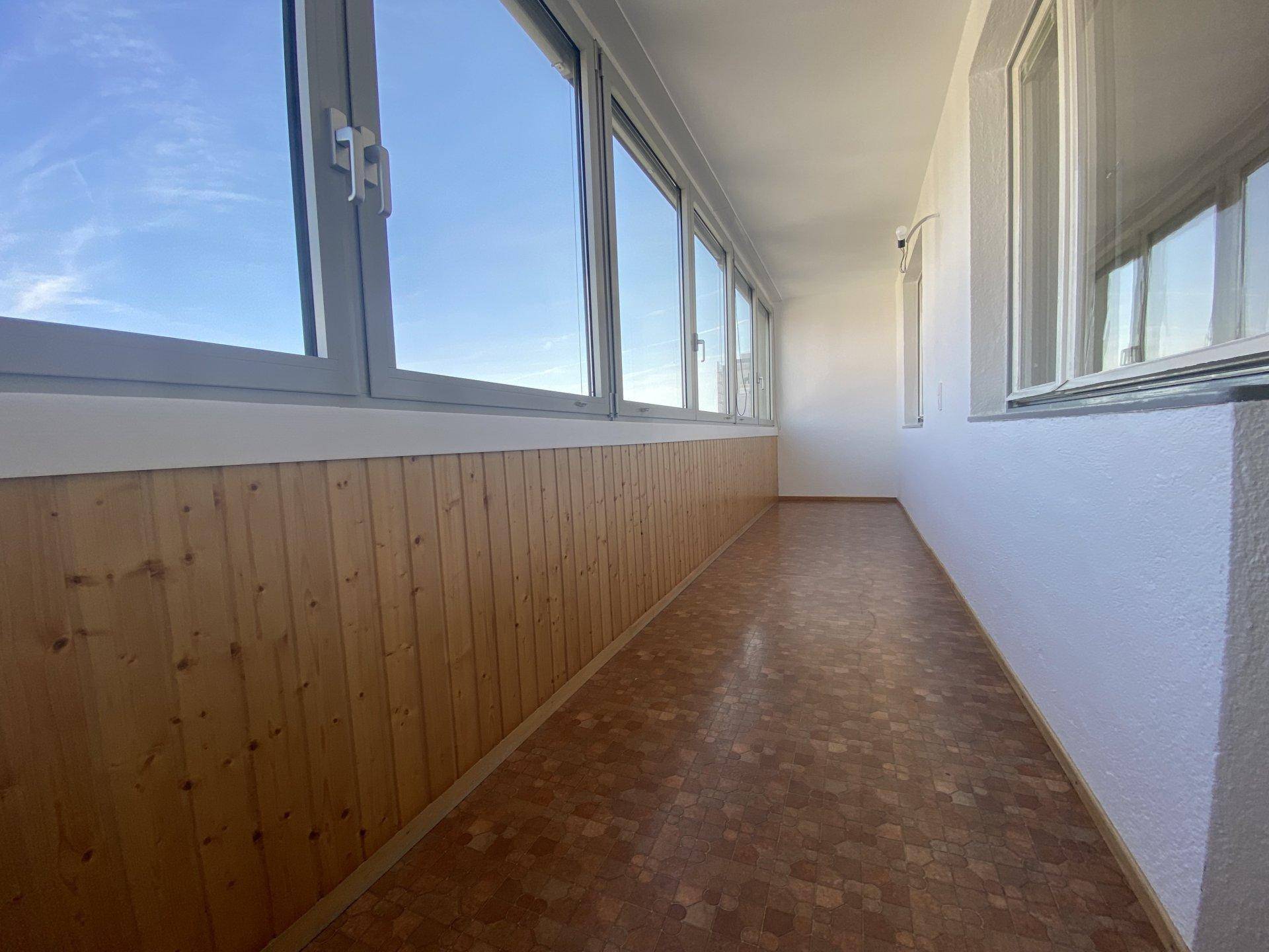 Verglaste Loggia mit Holzverkleidung und weitem Blick, ideal für entspannte Stunden.