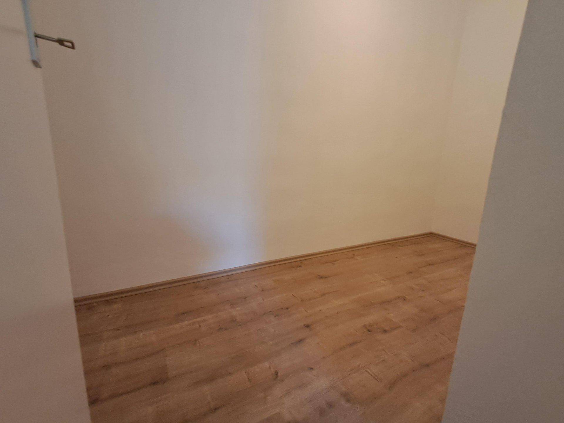Kleiner, leerer Raum mit Laminatboden und hellen Wänden, ideal als Abstellraum.