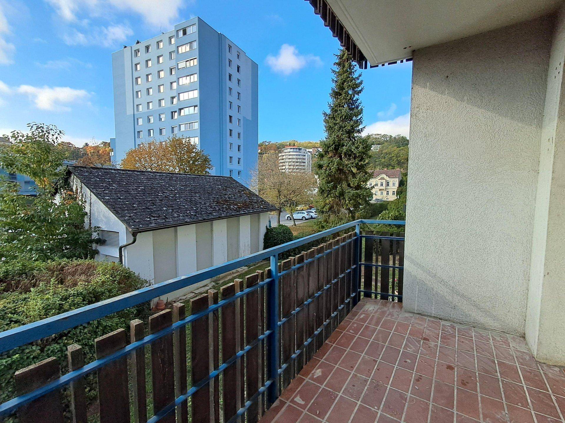 Balkon mit Fliesenboden und blauem Geländer, bietet Blick auf die Umgebung.