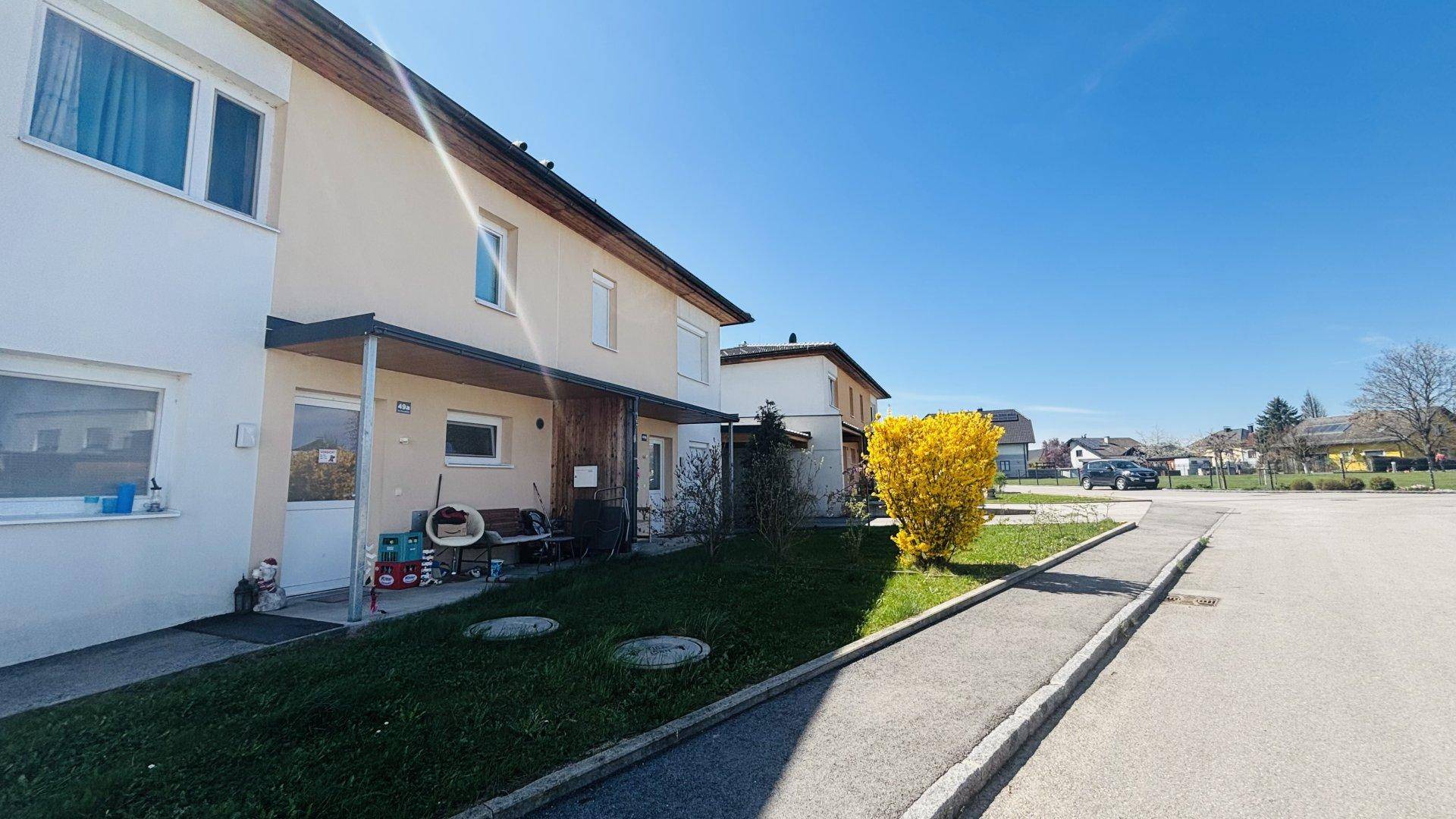 Seitenansicht der Doppelhaushälfte mit Zugang zum Eingangsbereich und angrenzender Straße.