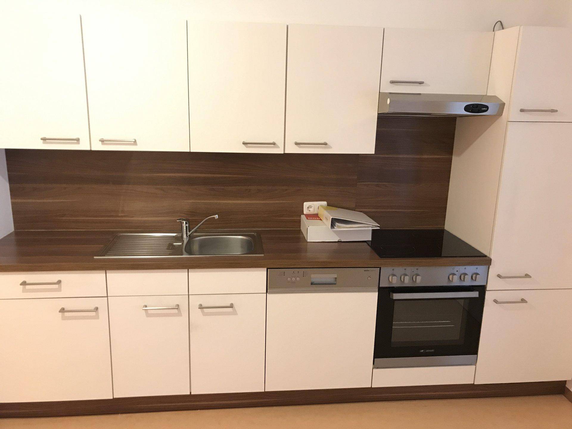 Moderne Einbauküche mit weißen Schränken, Holzoptik-Rückwand und integrierten Geräten.