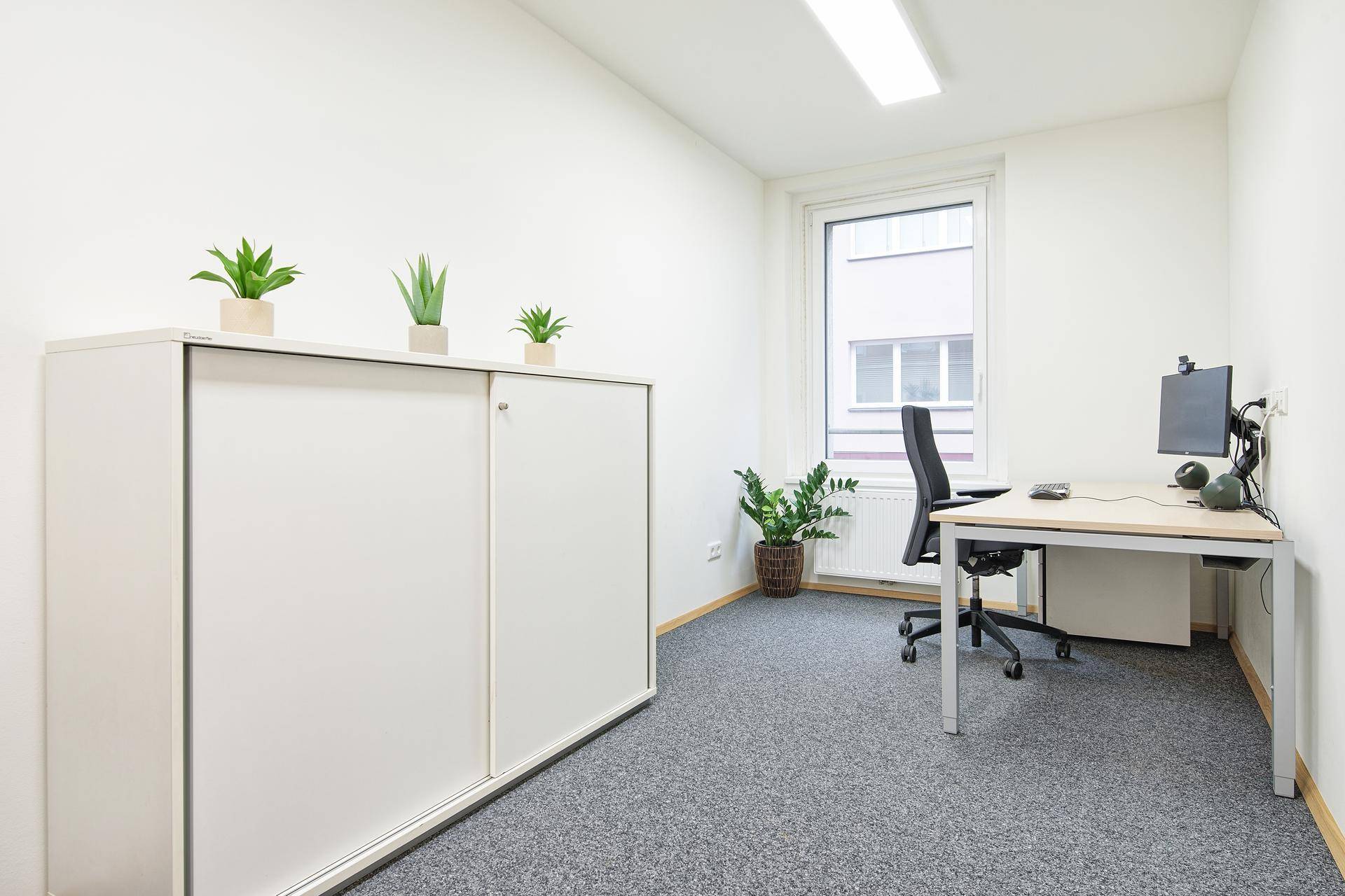 Helles und gepflegtes Büro mit weißem Schrank, Schreibtisch und Blick auf die Stadt.