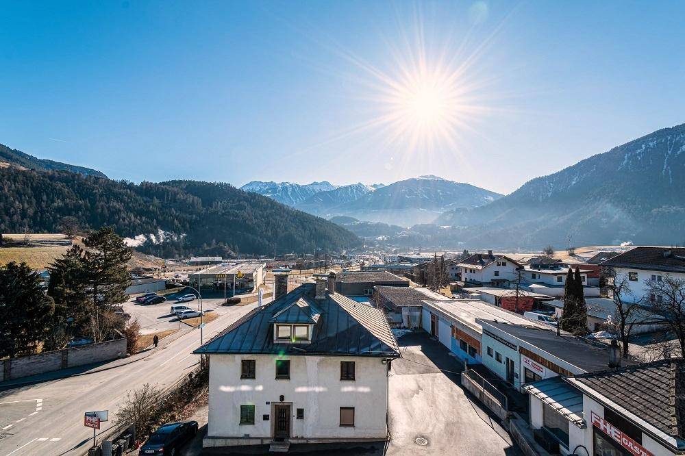 Weitläufiger Blick über die Umgebung mit Bergen und umliegenden Häusern unter strahlendem Himmel.