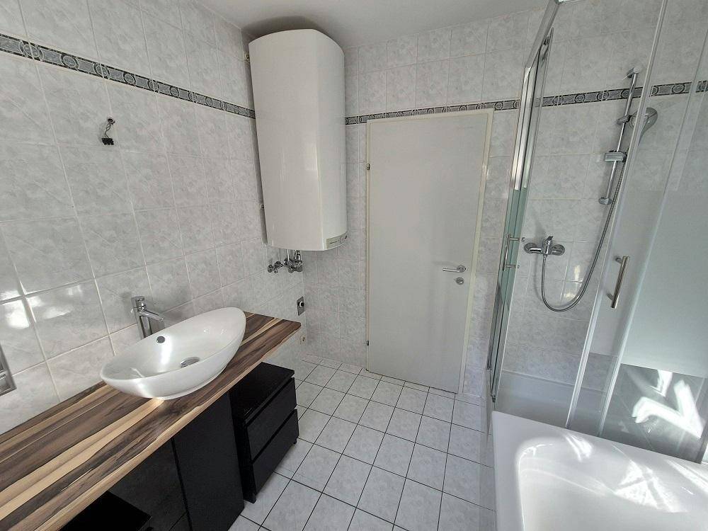 Modernes Badezimmer mit Waschtisch, Dusche und Badewanne, hell gefliest.