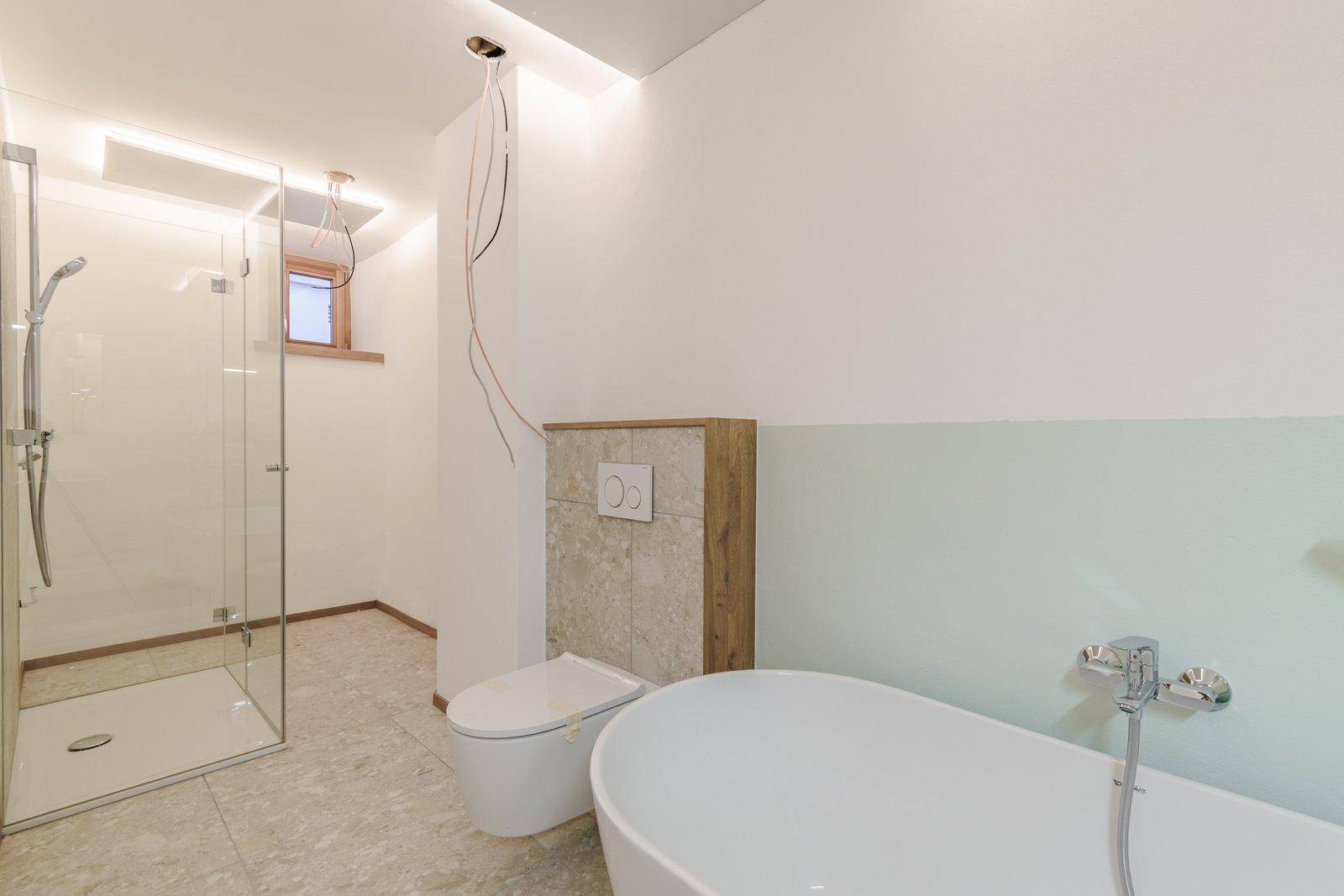 Modernes Badezimmer im Bau mit freistehender Badewanne, wandhängendem WC und begehbarer Dusche.