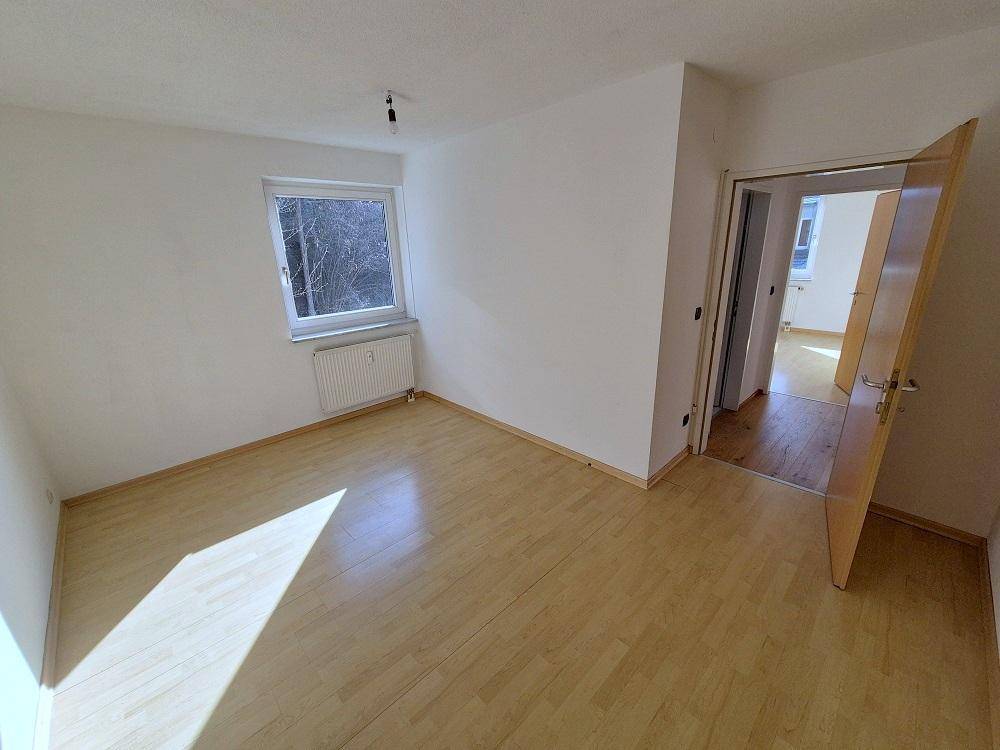 Helles Schlafzimmer mit Laminatboden und Fenster, das viel Tageslicht bietet.