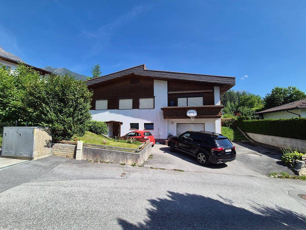 Das Haus präsentiert sich in einer ländlichen Umgebung mit viel Grün und Bergblick.