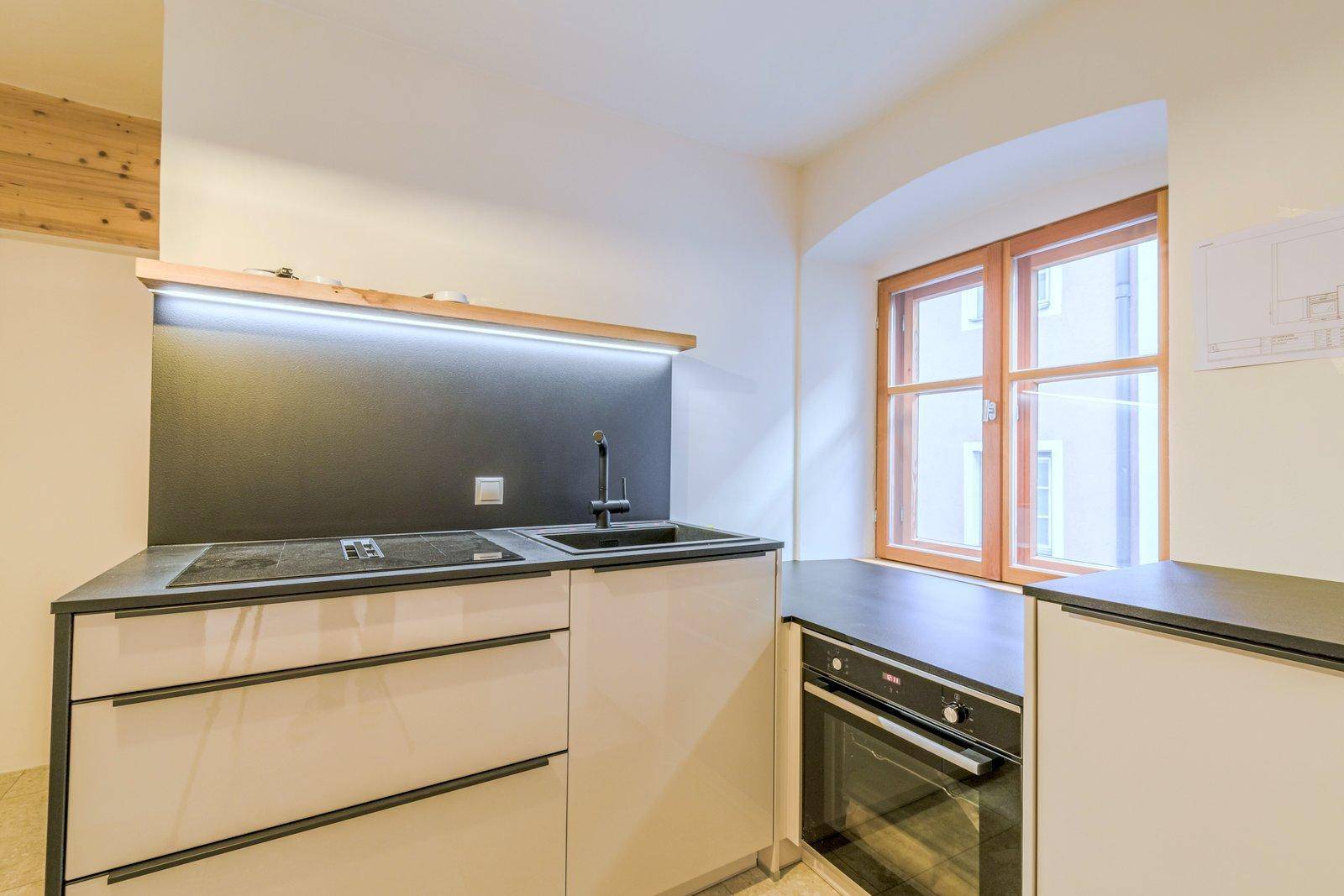 Detailansicht einer modernen Küchenzeile mit Induktionskochfeld, Spüle und integriertem Backofen.